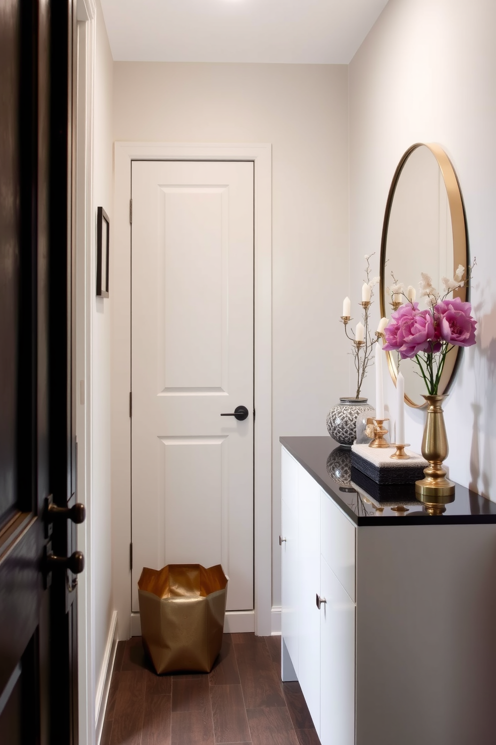 A narrow foyer featuring a small coat closet seamlessly integrated into the design. The walls are painted in a soft neutral tone, and a stylish console table sits against one side, adorned with decorative items and a mirror above.