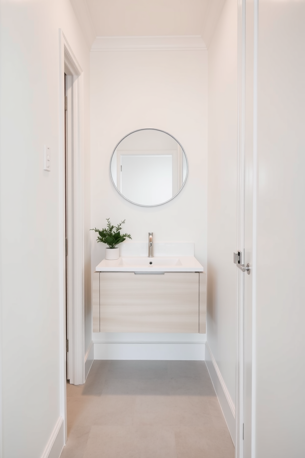 A narrow powder room filled with light colors to create an airy feel. The walls are painted in soft white, complemented by a delicate pastel accent on the trim. A sleek floating vanity with a light wood finish is positioned against one wall. Above the vanity, a round mirror with a thin metallic frame enhances the sense of space. The floor features light gray tiles that visually expand the room. A small potted plant adds a touch of greenery next to the vanity, bringing life to the design.