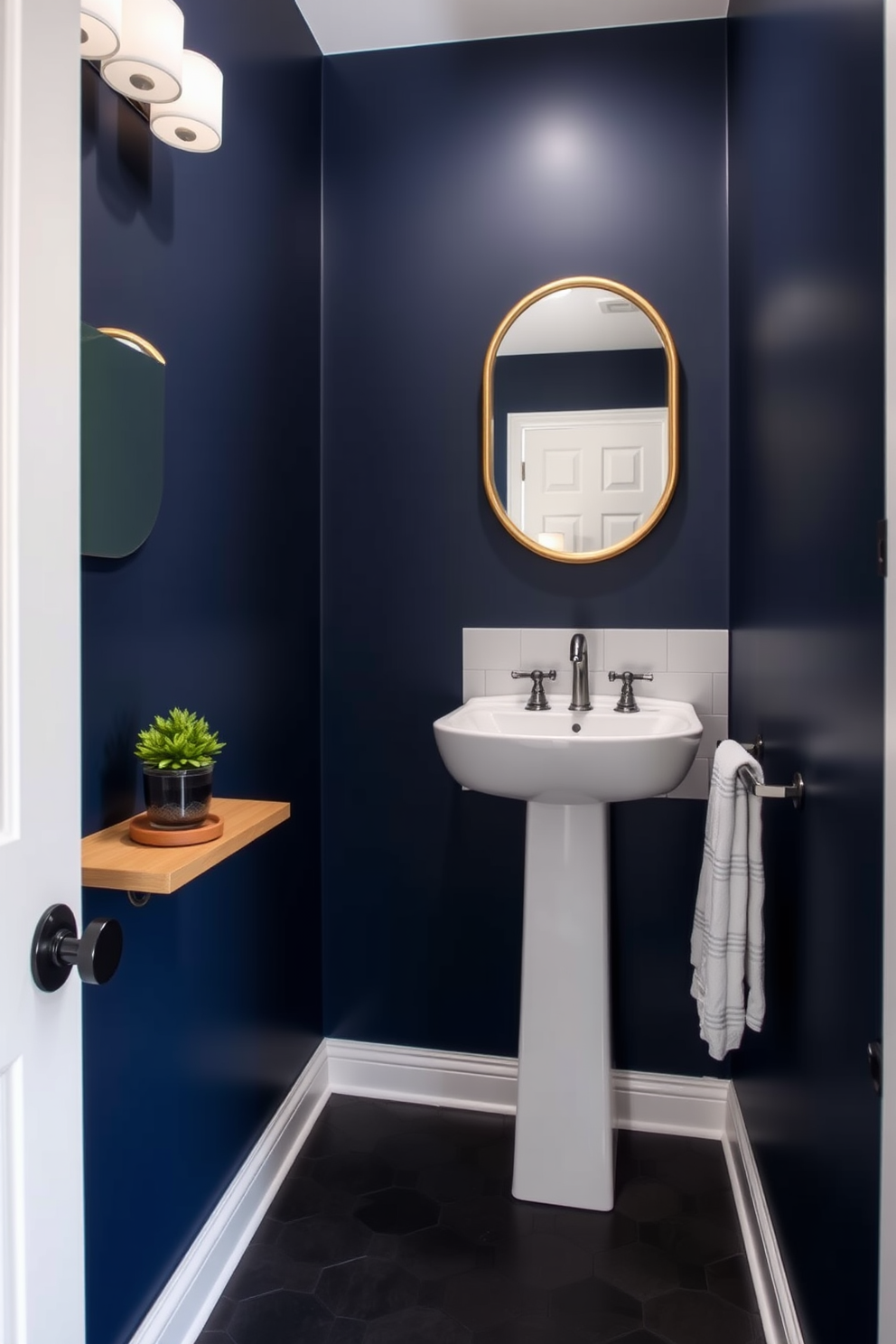 A narrow powder room with bold paint color creating a dramatic effect. The walls are painted in a deep navy blue, complemented by a sleek white pedestal sink and a gold-framed mirror above it. The floor features dark hexagonal tiles that add depth to the space. A small potted plant sits on a floating shelf, bringing a touch of greenery to the striking design.