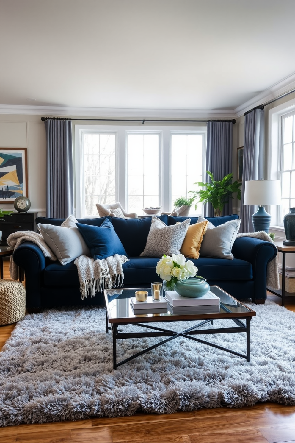 A cozy living room featuring a navy blue sofa adorned with layered textiles in various shades of blue and cream. The sofa is complemented by plush throw pillows and a textured blanket, creating an inviting atmosphere. In the background, a stylish coffee table sits atop a soft area rug, enhancing the room's warmth. Large windows allow natural light to flood in, illuminating the space and highlighting the elegant decor.