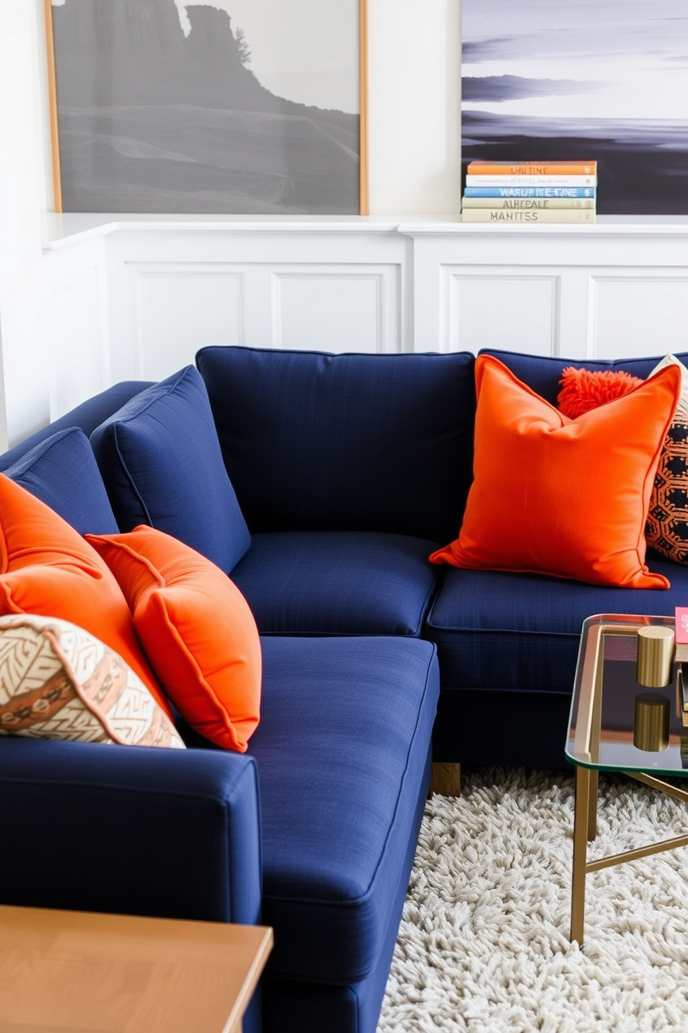 A stylish living room featuring a navy sofa adorned with bright orange pillows that create a vibrant contrast. The walls are painted in a soft white, and a plush area rug in neutral tones anchors the seating area.