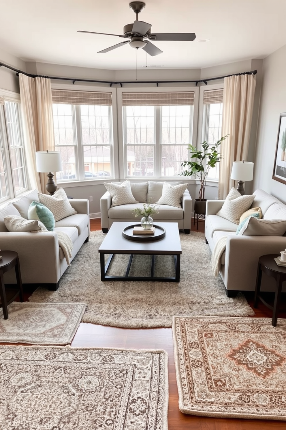 A cozy living room adorned with layered rugs that create warmth and depth. The space features a neutral color palette with soft beige and light gray tones complemented by plush seating and textured throw pillows. In the center, a large area rug anchors the seating arrangement, while smaller accent rugs add visual interest. Natural light pours in through large windows, illuminating the inviting atmosphere of the room.