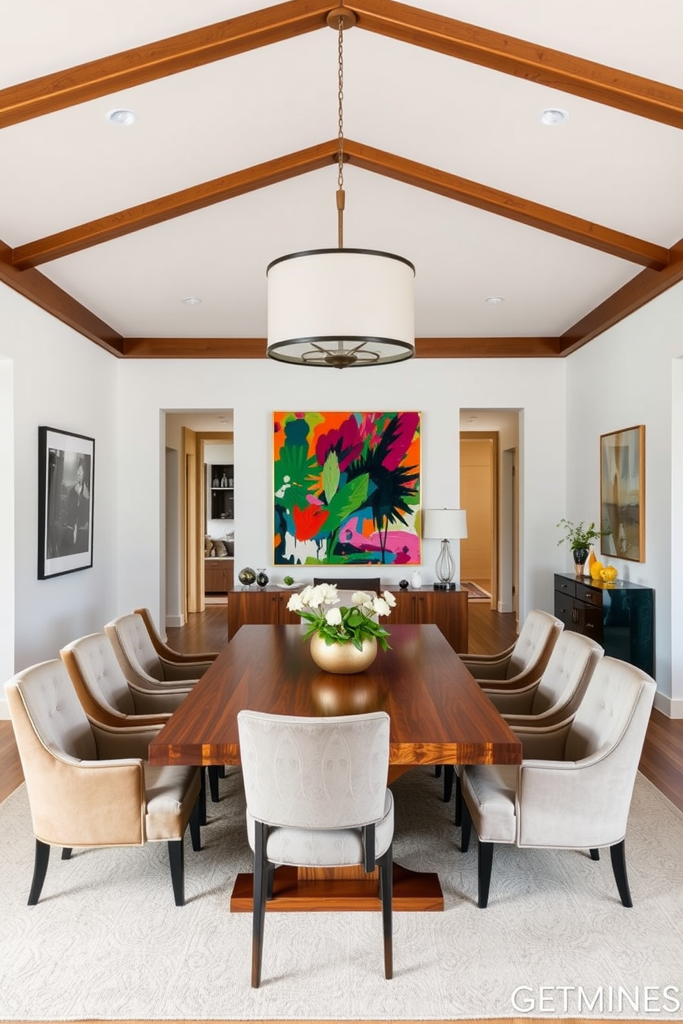 A stylish dining area within an open floor plan. The space features a large wooden dining table surrounded by upholstered chairs, with a statement chandelier hanging above. Artwork is hung on the walls to create a defined dining space. A vibrant painting is positioned prominently, complementing the overall color scheme of the room.