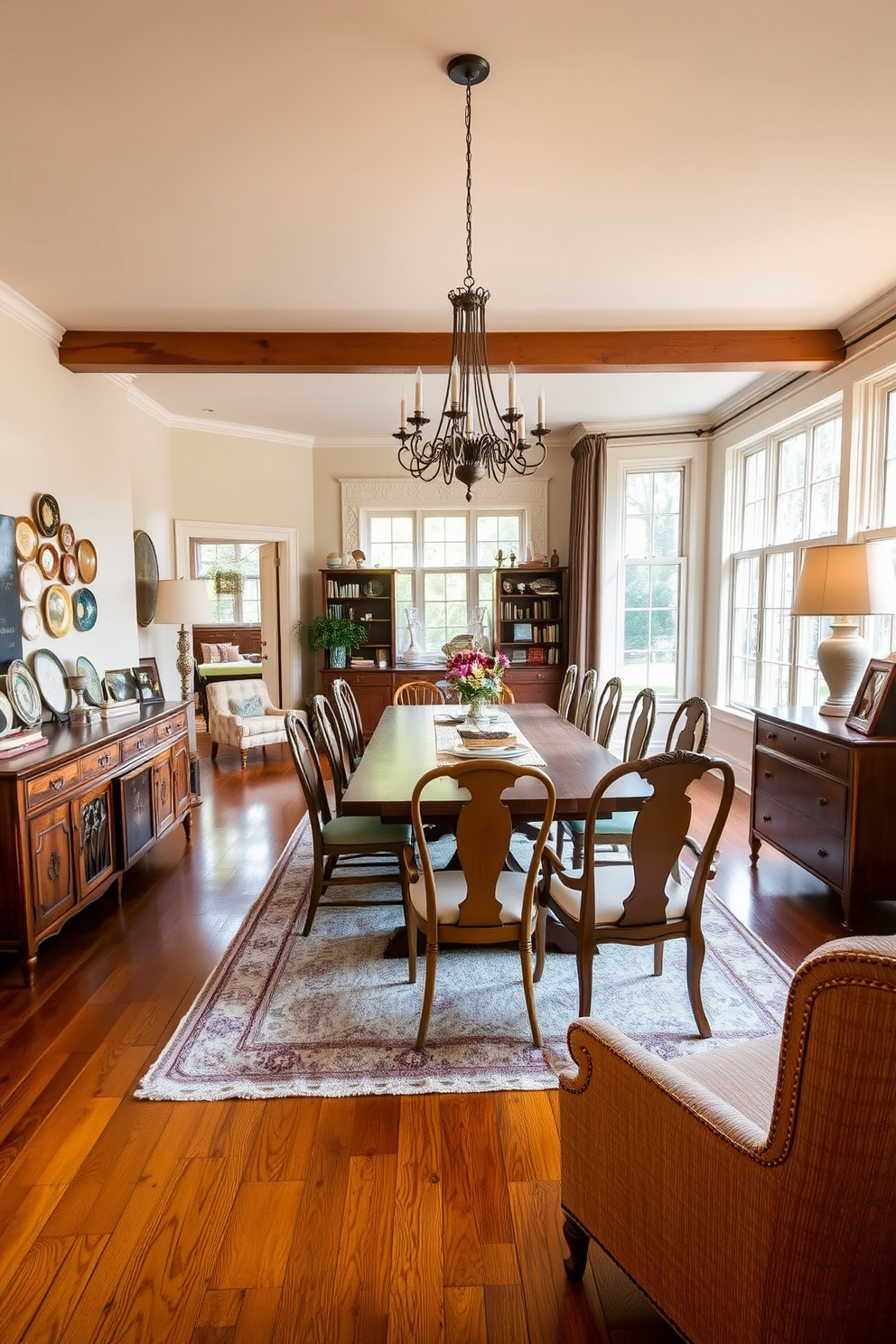 A spacious open floor plan dining room features a large wooden dining table surrounded by mismatched vintage chairs that add character and charm. A striking chandelier hangs overhead, illuminating the room's warm color palette of soft creams and rich browns. On one side of the room, a vintage sideboard displays an array of decorative plates and a collection of antique books. Large windows allow natural light to flood in, highlighting a cozy seating area with a plush, patterned rug beneath a pair of inviting armchairs.