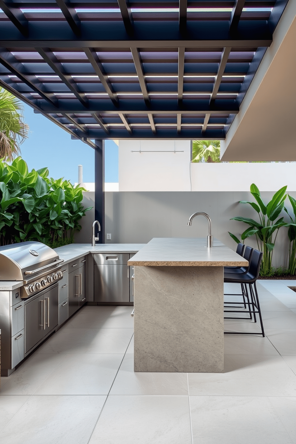 A modern outdoor kitchen featuring sleek lines and a minimalist design. The space includes a stainless steel grill, a large stone countertop with bar seating, and integrated storage solutions. Surrounding the kitchen are lush green plants and a stylish pergola for shade. The flooring is made of large, neutral-colored tiles that complement the contemporary aesthetic.