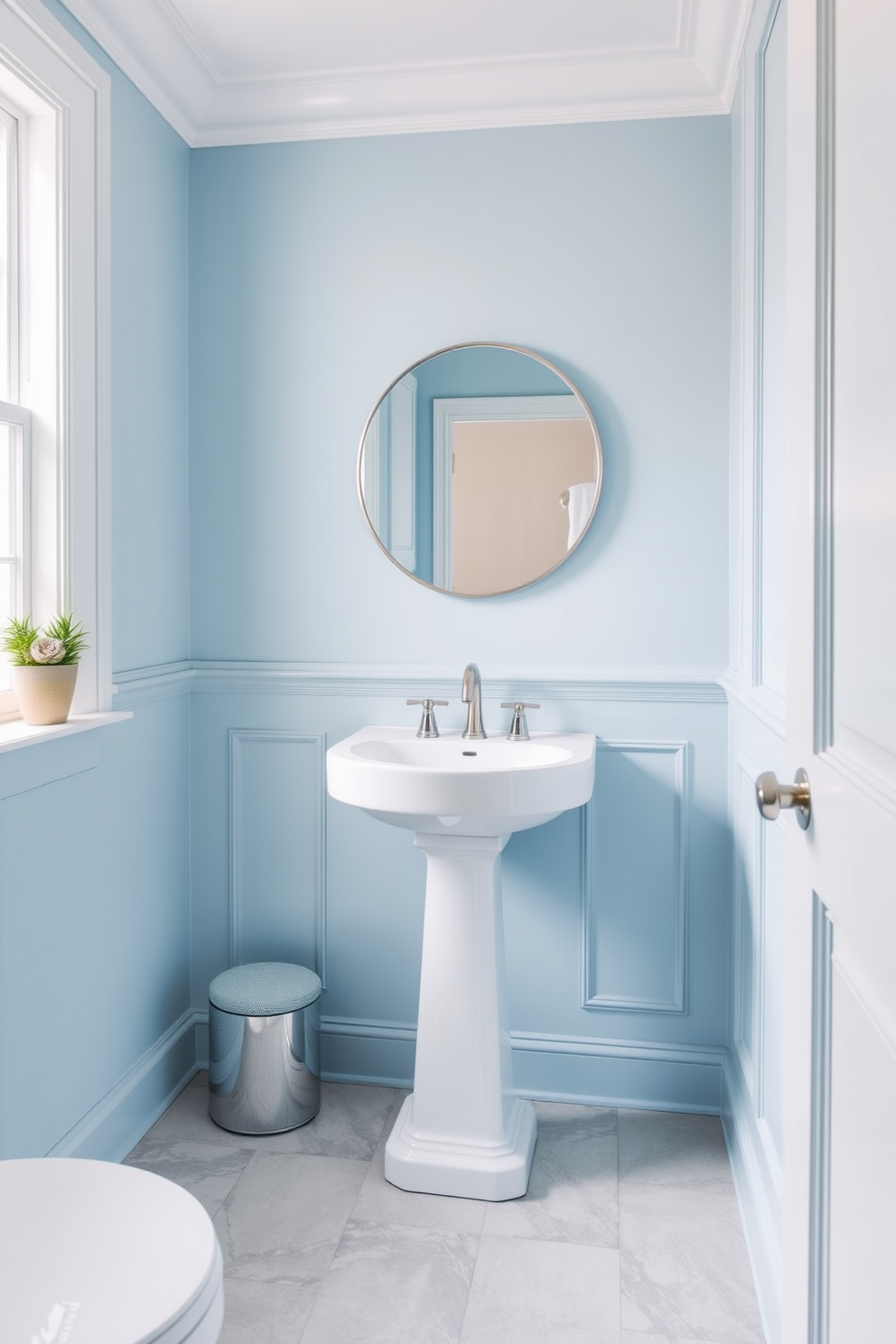 A serene powder room with sky blue walls that create an airy and refreshing atmosphere. The space features a sleek white pedestal sink and a round mirror with a simple silver frame, enhancing the lightness of the room. The floor is adorned with light gray tiles that complement the blue walls, adding a subtle contrast. A small potted plant sits on the windowsill, bringing a touch of nature into the elegant design.