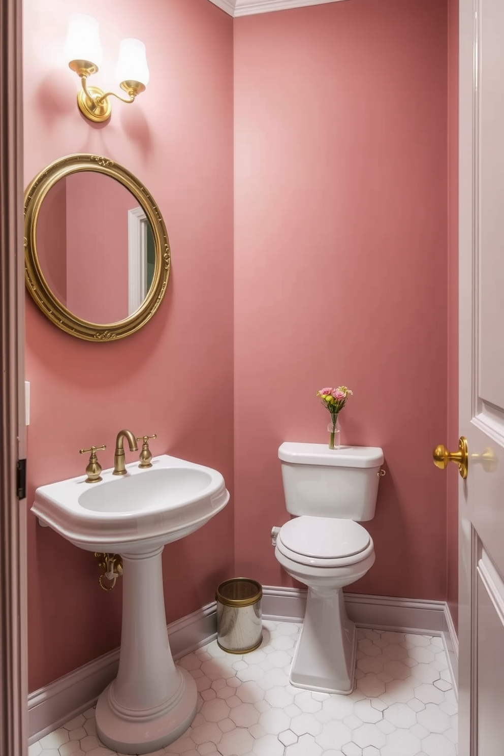 A charming powder room featuring dusty rose walls that evoke a sense of vintage elegance. The space is adorned with a classic pedestal sink and a round mirror framed in antique gold, complemented by brass fixtures. The floor is covered in white hexagonal tiles, adding a touch of modern contrast. A small wooden shelf holds neatly rolled towels and a delicate vase of fresh flowers, enhancing the inviting atmosphere.