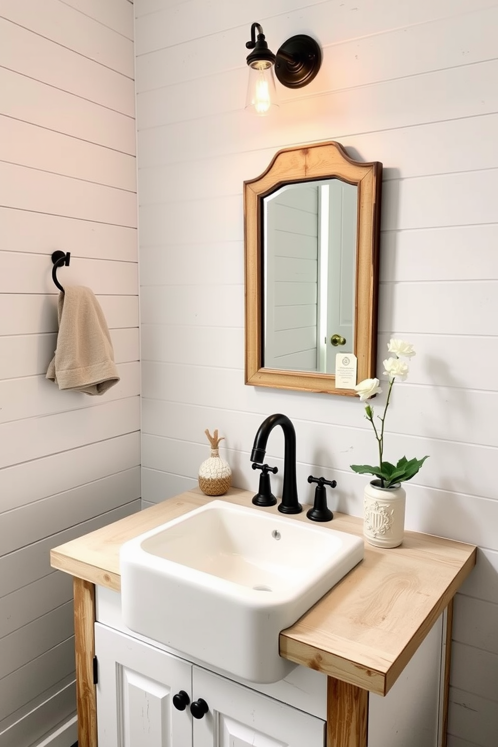 A charming powder room featuring a farmhouse sink with an apron front. The sink is complemented by a rustic wooden vanity topped with a distressed white countertop. The walls are adorned with shiplap in a soft gray hue, enhancing the farmhouse aesthetic. A vintage-style mirror hangs above the sink, reflecting warm light from a stylish wall sconce.