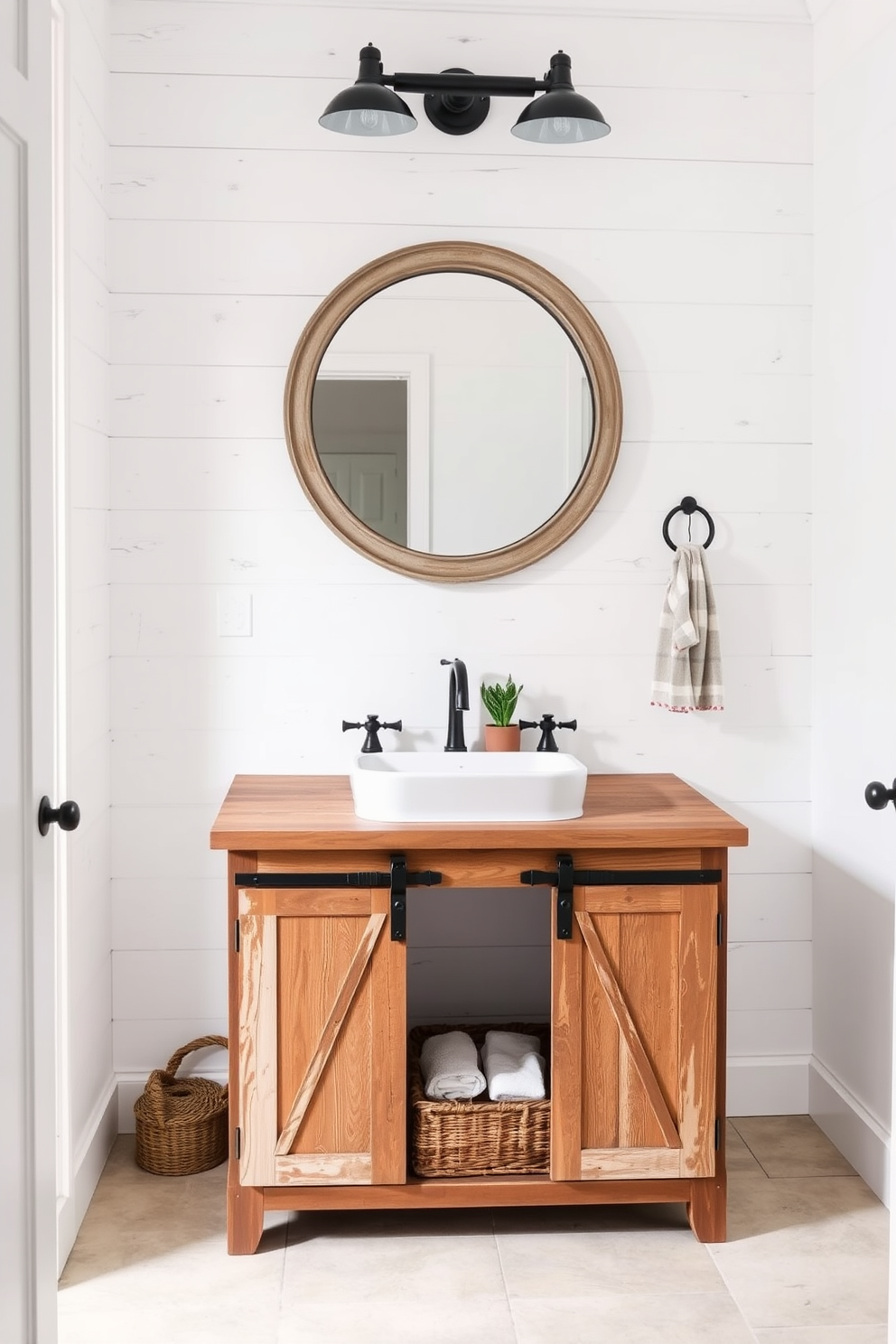 A charming farmhouse powder room featuring a rustic vanity with barn door accents. The vanity is made of reclaimed wood and includes a deep farmhouse sink with vintage-style faucets. The walls are adorned with shiplap in a soft white hue, complemented by a large round mirror with a distressed frame. A woven basket sits beneath the vanity, filled with rolled towels, and a small potted plant adds a touch of greenery.