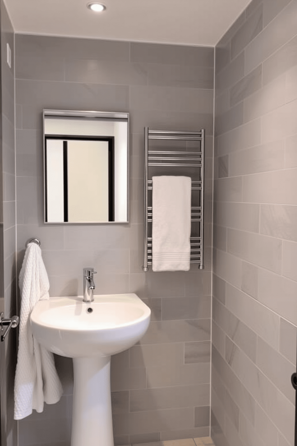 A stylish quarter bathroom features a foldable towel rack that adds versatility and saves space. The walls are adorned with light gray tiles, and a sleek pedestal sink complements the modern aesthetic.