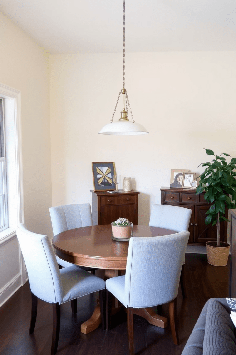 Create a cozy dining area featuring a round wooden table surrounded by upholstered chairs. The walls are painted in a soft cream color, and a pendant light hangs gracefully above the table, casting a warm glow. To one side of the table, a small sideboard displays decorative items and serves as additional storage. A vibrant potted plant sits in the corner, adding a touch of greenery to the inviting space.