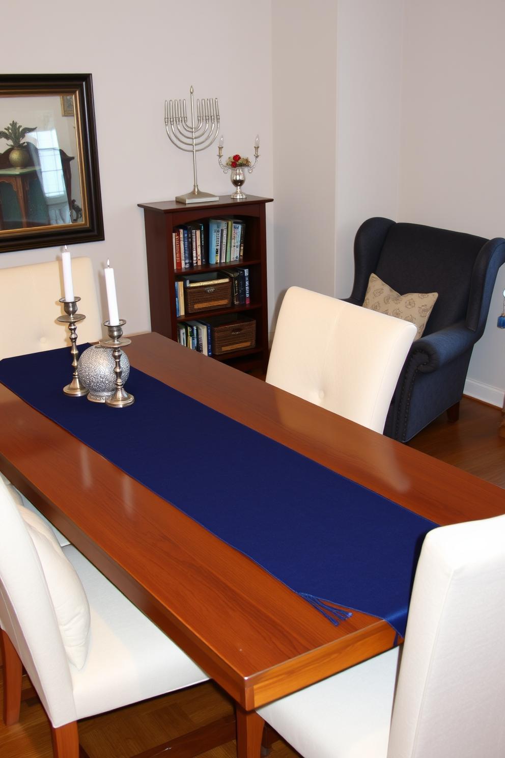 A festive table runner in blue is elegantly draped across a wooden dining table adorned with silver and white accents. Surrounding the table are plush chairs with soft cushions, creating a cozy atmosphere for holiday gatherings. In the corner of the room, a reading nook is set up with a comfortable armchair upholstered in a rich fabric. A small bookshelf filled with holiday-themed books and a decorative menorah complete the inviting space, perfect for celebrating Hanukkah.