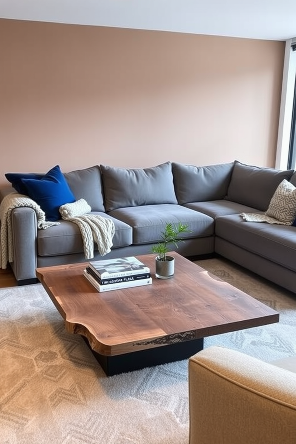 A modern living room featuring layered textures with a mix of fabrics and materials. Plush velvet cushions in deep blue are arranged on a large, soft gray sectional sofa, complemented by a chunky knit throw draped over one arm. A sleek coffee table made of reclaimed wood sits in the center, adorned with a stack of art books and a small potted plant. The walls are painted in a warm taupe, and a large area rug with geometric patterns anchors the seating area.