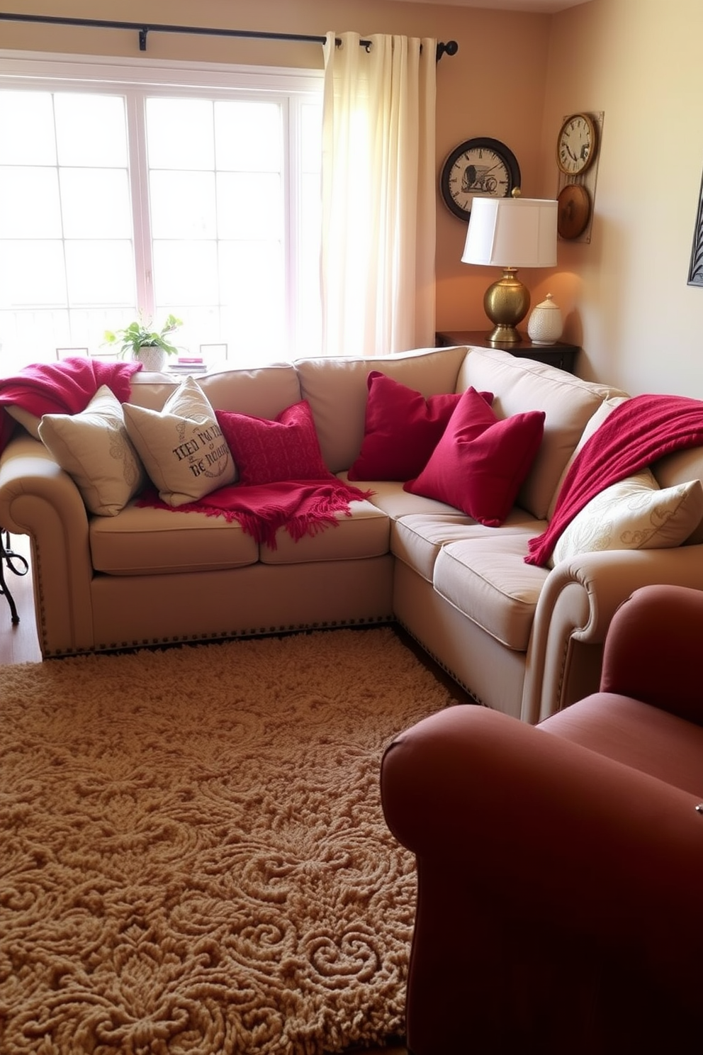 A cozy family room featuring a beige couch adorned with soft red throws. The room is filled with warm lighting and has a plush area rug that complements the color scheme.