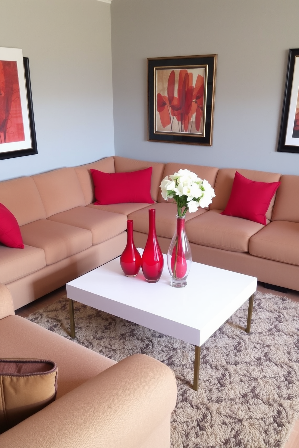 A cozy family room features a large sectional sofa in a warm beige fabric, complemented by vibrant red accent pillows. In the center, a stylish coffee table holds two striking red vases filled with fresh white flowers, adding a pop of color to the space. The walls are painted in a soft gray tone, enhancing the room's inviting atmosphere. A plush area rug anchors the seating arrangement, while framed artwork with red accents adorns the walls, tying the design together.