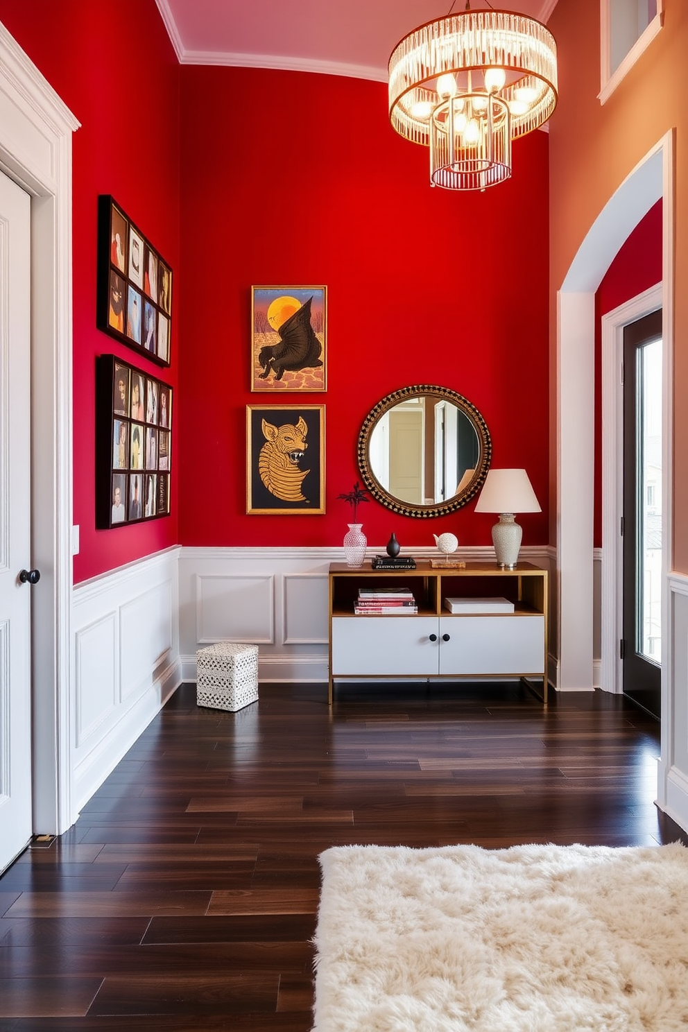 A bold red accent wall serves as the focal point of the foyer, adorned with a curated display of vibrant artwork that adds personality and warmth. The flooring is a sleek dark hardwood, complementing the richness of the red while a stylish console table sits against the wall, topped with decorative items and a mirror above. The foyer is illuminated by a modern chandelier that casts a warm glow, enhancing the inviting atmosphere. To the side, a plush area rug anchors the space, providing comfort and a touch of elegance to the entryway.