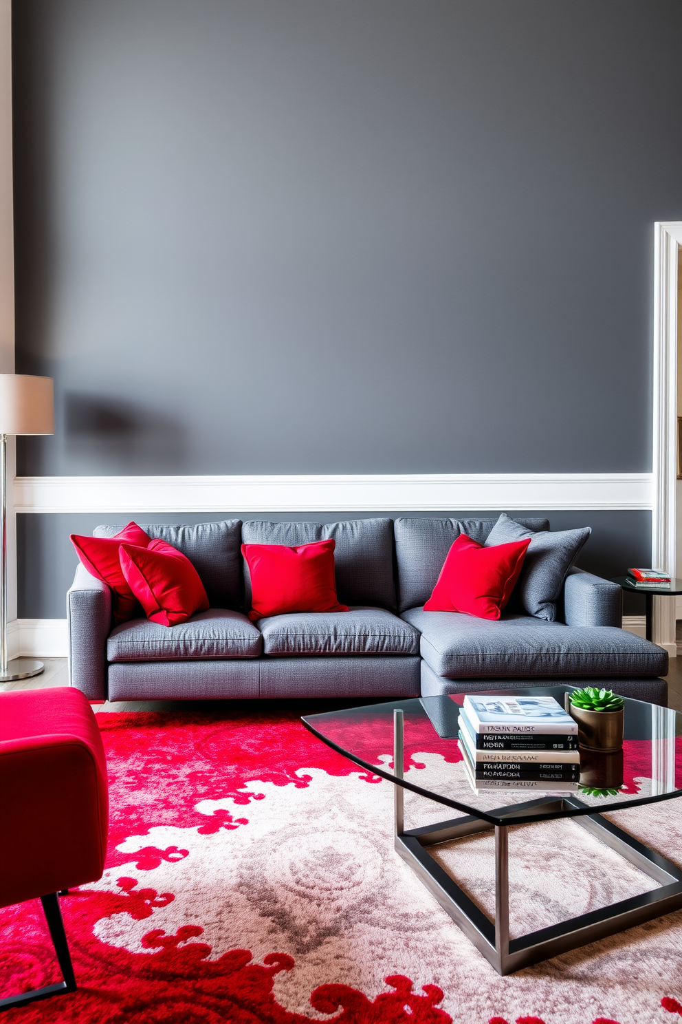 A sophisticated living room setting featuring a red and gray color scheme. The walls are painted a deep gray while bold red accents are incorporated through plush throw pillows and a vibrant area rug. A sleek gray sectional sofa is positioned in the center, complemented by a stylish red accent chair. A modern coffee table with a glass top sits atop the area rug, adorned with a few decorative books and a small plant.