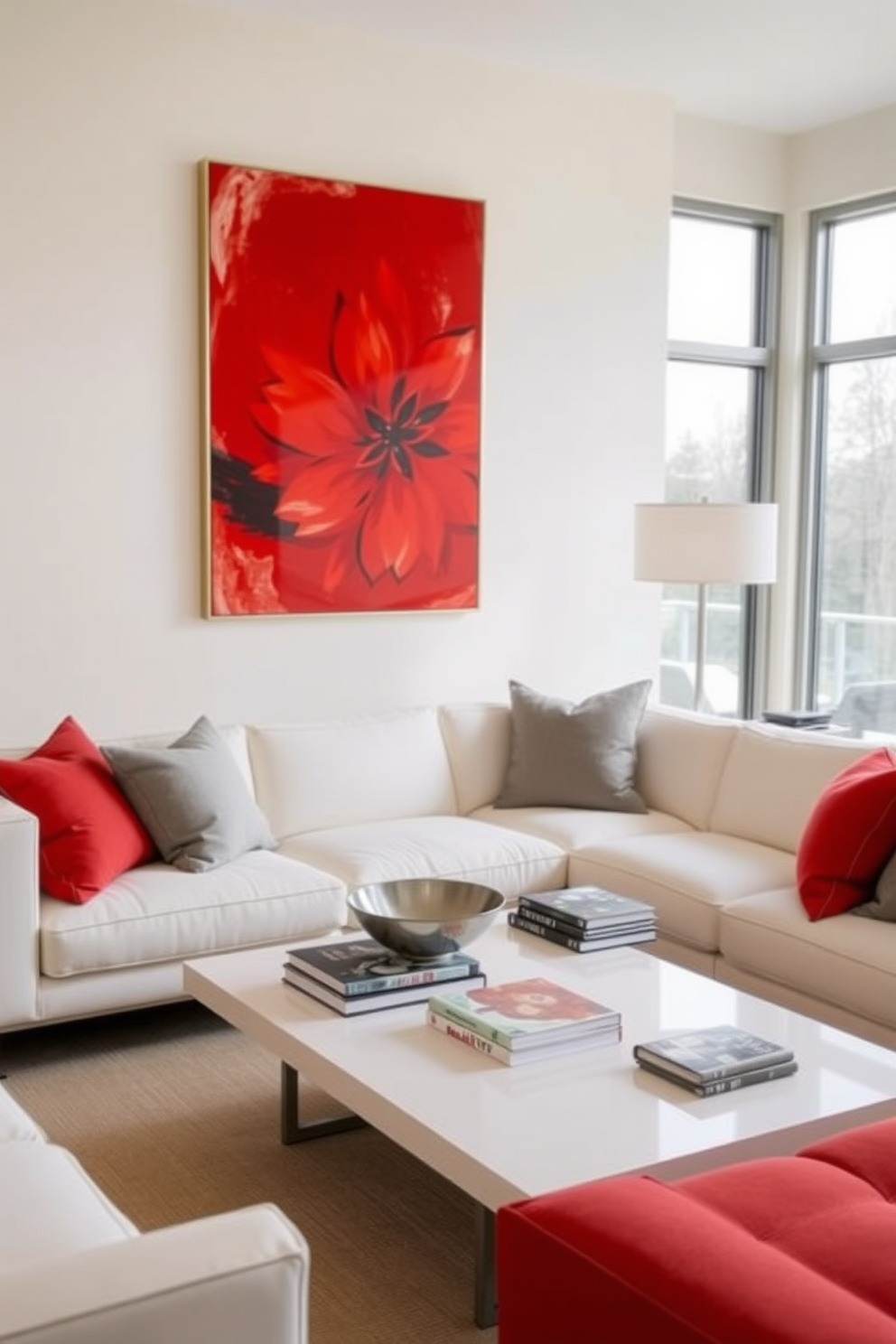 A vibrant red artwork is displayed prominently on the wall, contrasting beautifully with the light-colored walls of the room. The space features a plush white sofa adorned with red and gray throw pillows, creating a cohesive color scheme. A sleek coffee table sits in the center, topped with a decorative bowl and a stack of art books. Large windows allow natural light to flood the room, enhancing the bright and airy atmosphere.