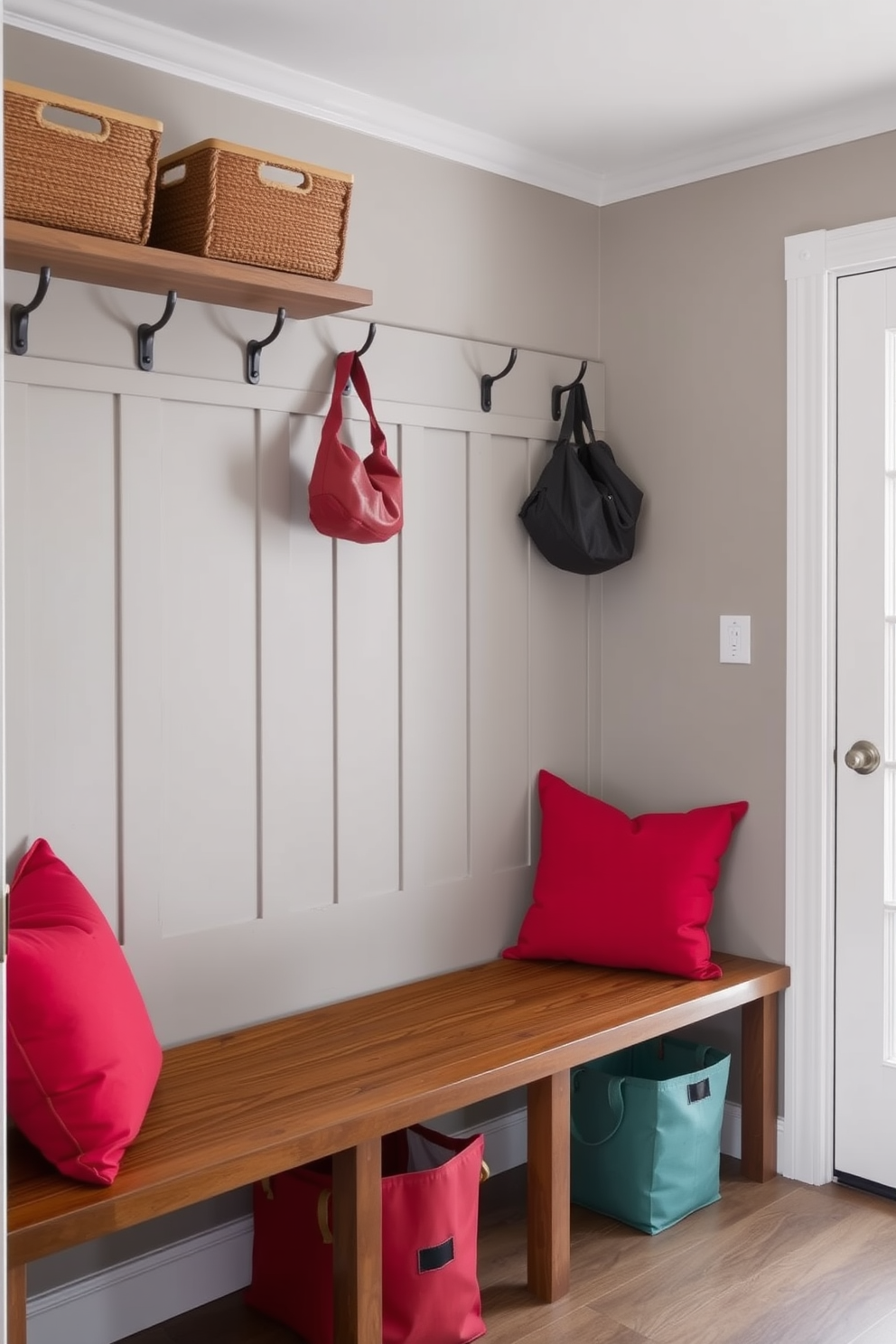 A cozy mudroom featuring a wooden bench adorned with vibrant red cushions. The walls are painted in a soft gray tone, and there are hooks for hanging coats and bags above the bench.