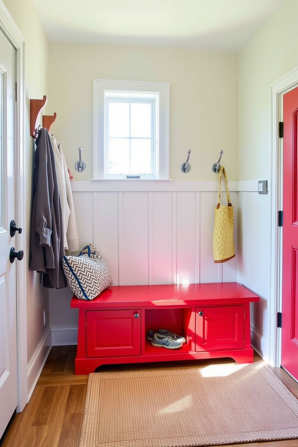 A vibrant red bench with ample storage underneath sits against the wall, providing a functional yet stylish seating area. The mudroom features a combination of hooks and cubbies for organization, with a welcoming rug laid out beneath the bench. The walls are painted in a soft neutral tone to complement the boldness of the red bench, creating a balanced and inviting atmosphere. Natural light streams in through a nearby window, illuminating the space and highlighting the thoughtful design elements.