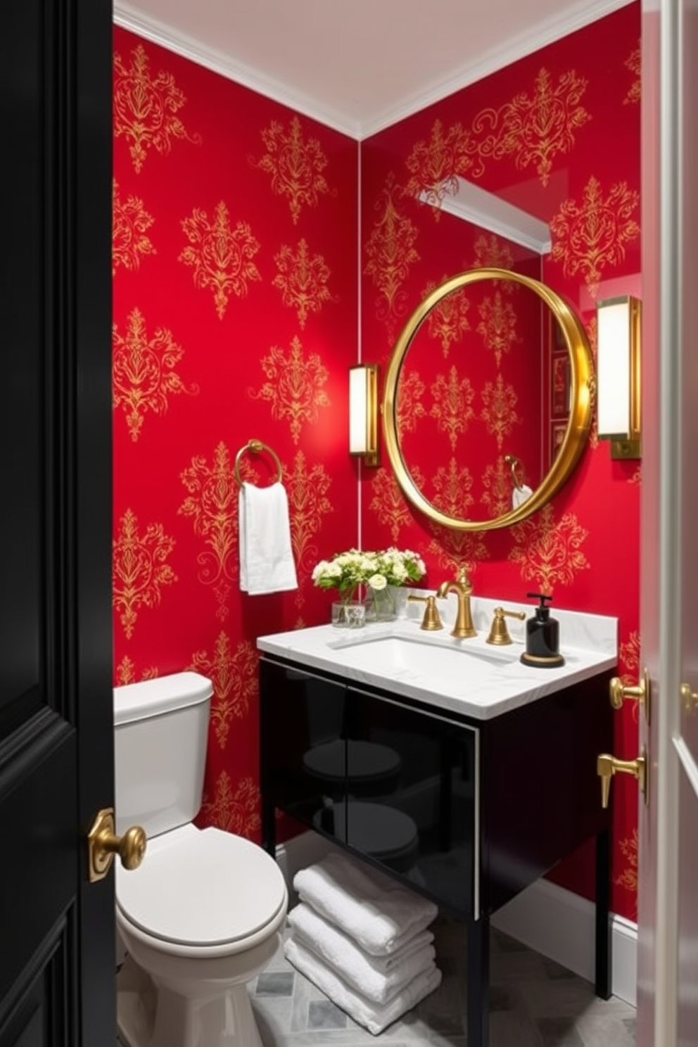 A striking powder room featuring bold red wallpaper adorned with intricate gold accents. The space is complemented by a sleek black vanity with a white marble sink and a large round mirror framed in gold.