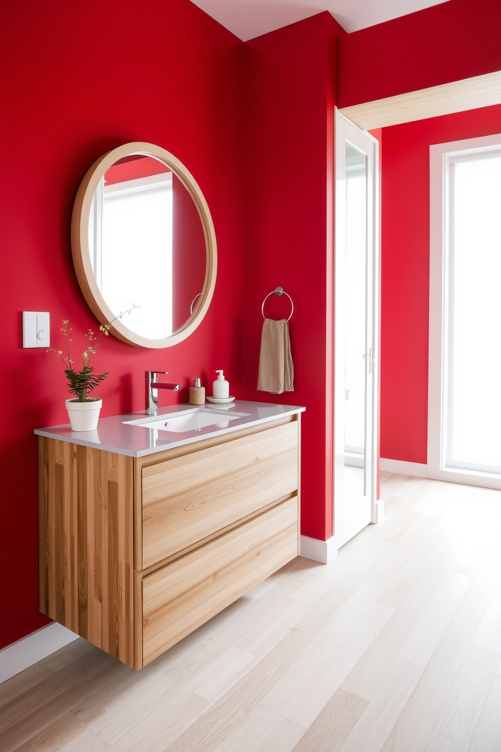 Striking red accents bring a bold energy to the space, complemented by natural wood elements that add warmth and texture. The walls are painted in a deep red hue, while the wooden vanity features a sleek design with a polished finish, creating a stunning contrast. The floor is adorned with light wood planks that enhance the room's brightness, and a round mirror with a wooden frame hangs above the vanity. Decorative elements include a small potted plant and a chic soap dispenser, both in neutral tones to balance the vibrant red accents.