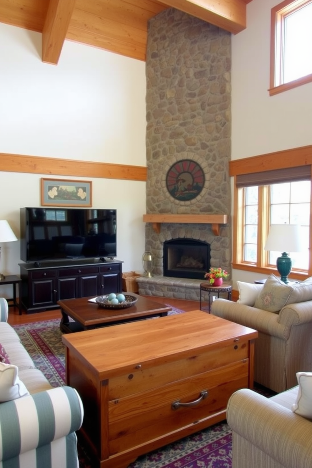 A cozy family room featuring a cedar chest that serves both as storage and additional seating. The room is adorned with warm wooden beams, a large stone fireplace, and comfortable seating arrangements that invite relaxation.