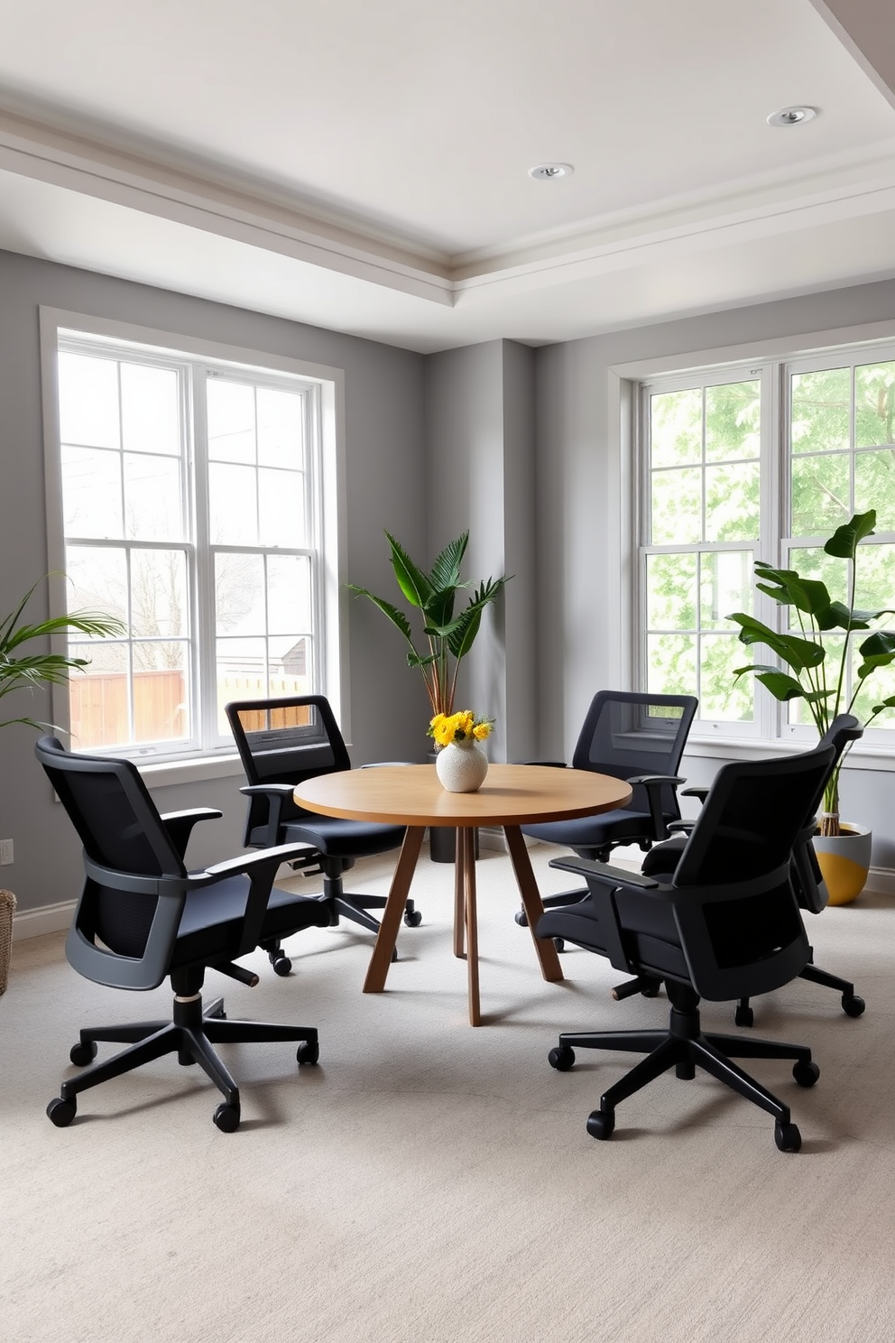 A modern shared home office featuring a round table at the center surrounded by comfortable ergonomic chairs. The walls are painted in a soft gray tone, and large windows allow natural light to flood the space, creating an inviting atmosphere for collaboration.