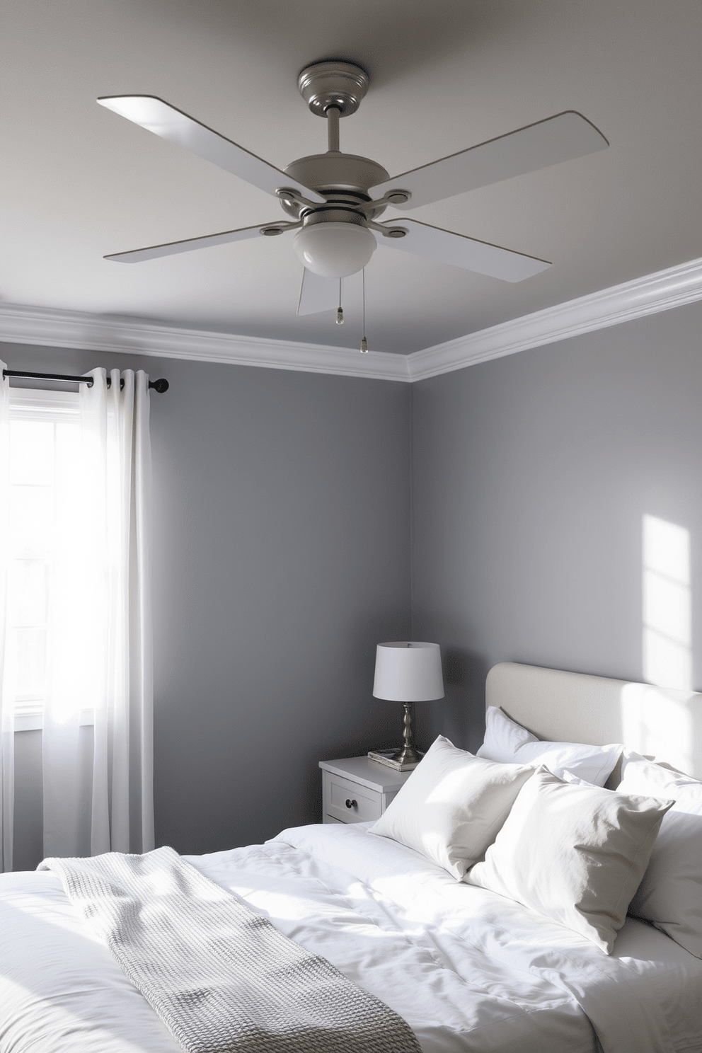 A serene bedroom retreat featuring a simple ceiling fan for airflow. The walls are painted in a soft gray hue, complemented by a cozy bed with white linens and a textured throw blanket. A minimalist nightstand stands beside the bed, topped with a small lamp and a few books. Natural light streams through sheer curtains, creating a warm and inviting atmosphere.