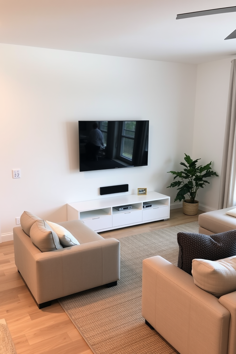 A cozy family room featuring a wall-mounted TV above a sleek minimalist stand. The space is filled with a soft sectional sofa in neutral tones, complemented by a textured area rug and a few decorative cushions.