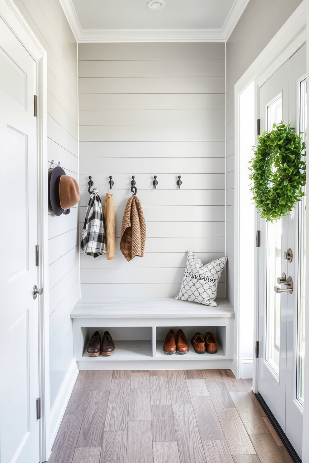 A functional mudroom featuring hooks for umbrellas and hats is designed with a light gray shiplap wall. The floor is covered in durable ceramic tiles that mimic the look of wood, providing both style and practicality. A bench with built-in storage sits below the hooks, offering a place to sit while putting on shoes. Bright natural light filters in through a nearby window, enhancing the welcoming atmosphere of the space.