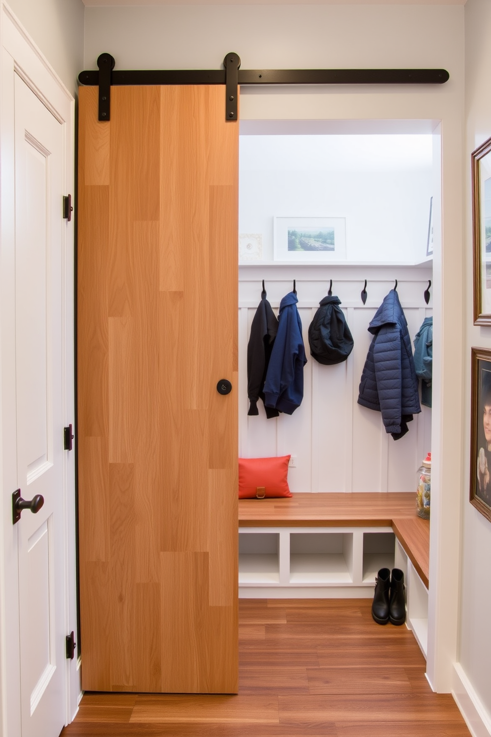 A stylish mudroom featuring a sliding barn door that opens to a well-organized space. The area includes built-in benches with storage underneath and hooks for coats, creating a functional and inviting entryway.