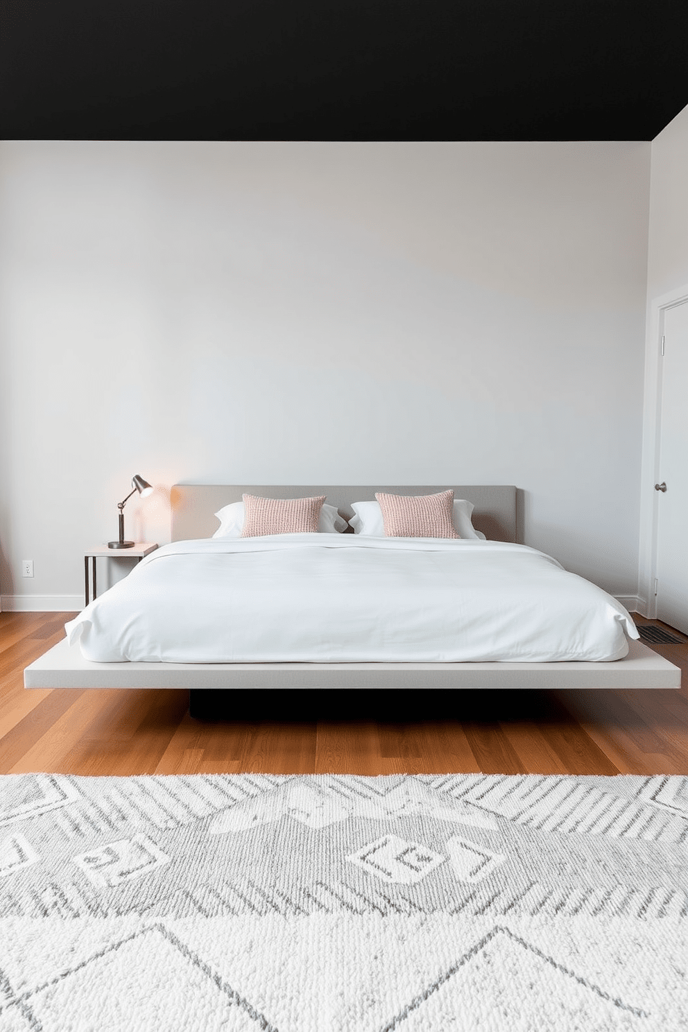 A sleek platform bed occupies the center of the room, featuring clean lines and a low profile. The bedding is a crisp white with textured throw pillows in soft pastels, enhancing the minimalist aesthetic. The walls are painted in a light gray, creating an airy feel, while a small bedside table holds a modern lamp with a warm glow. A plush area rug in a subtle geometric pattern adds warmth to the hardwood floor, completing the cozy yet sophisticated look.