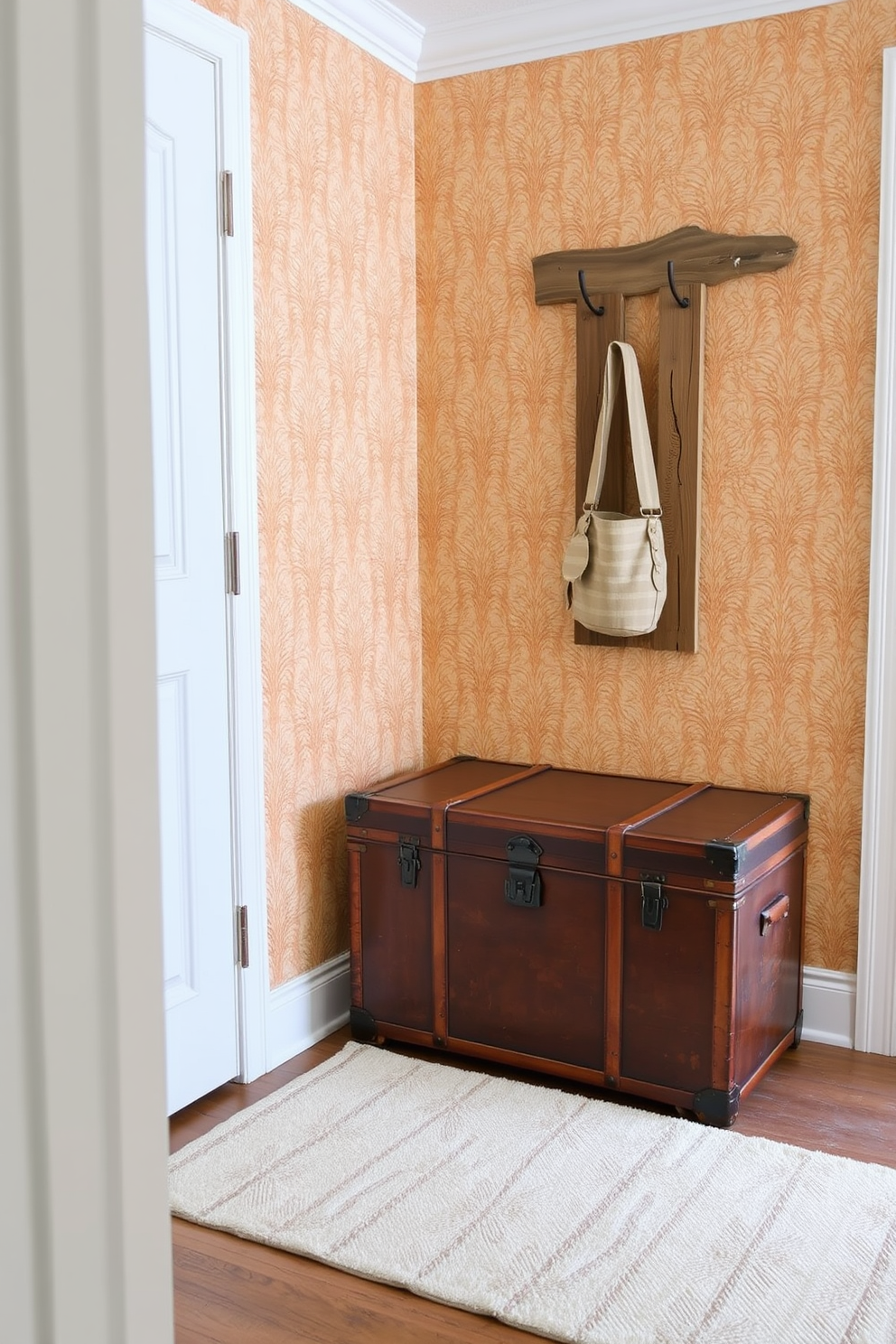 A vintage trunk serves as a stylish storage solution in a small entryway. It is placed against a wall adorned with warm-toned wallpaper, creating an inviting atmosphere. Next to the trunk, a sleek coat rack made of reclaimed wood adds functionality without overwhelming the space. A soft, patterned rug lies beneath, providing comfort and a touch of elegance to the entryway.