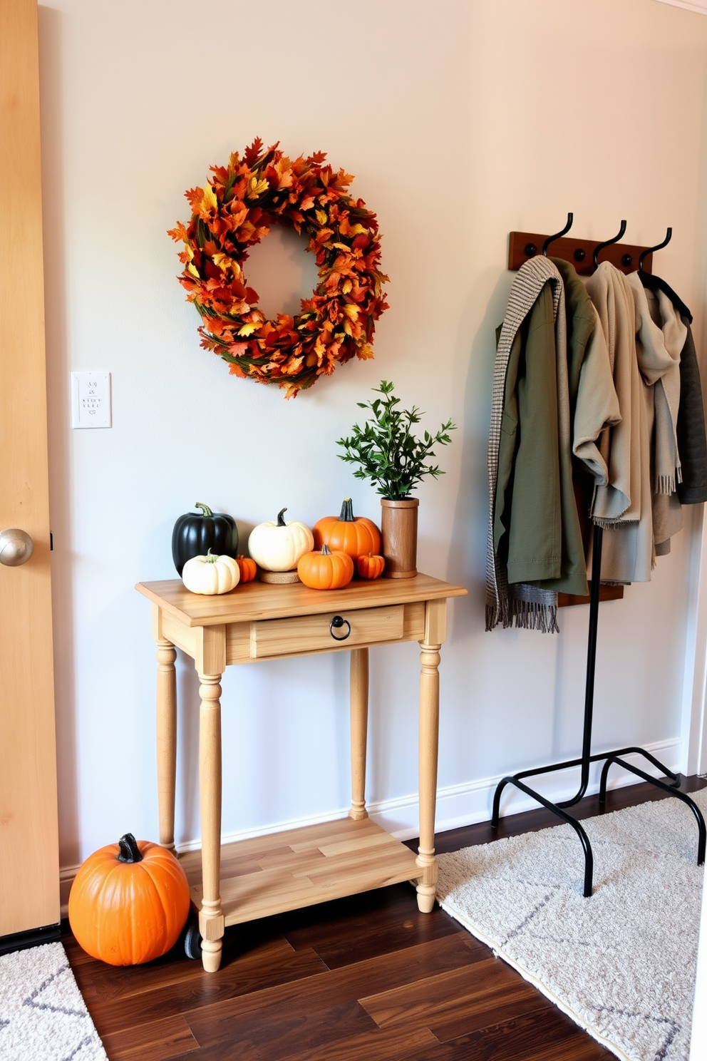 A cozy entryway adorned with seasonal decor. A small wooden console table is placed against the wall, decorated with a vibrant autumn wreath and a collection of pumpkins in varying sizes. To the right, a stylish coat rack holds a few lightweight jackets and scarves. The floor is covered with a soft, neutral rug that adds warmth, while a small potted plant brings a touch of greenery to the space.