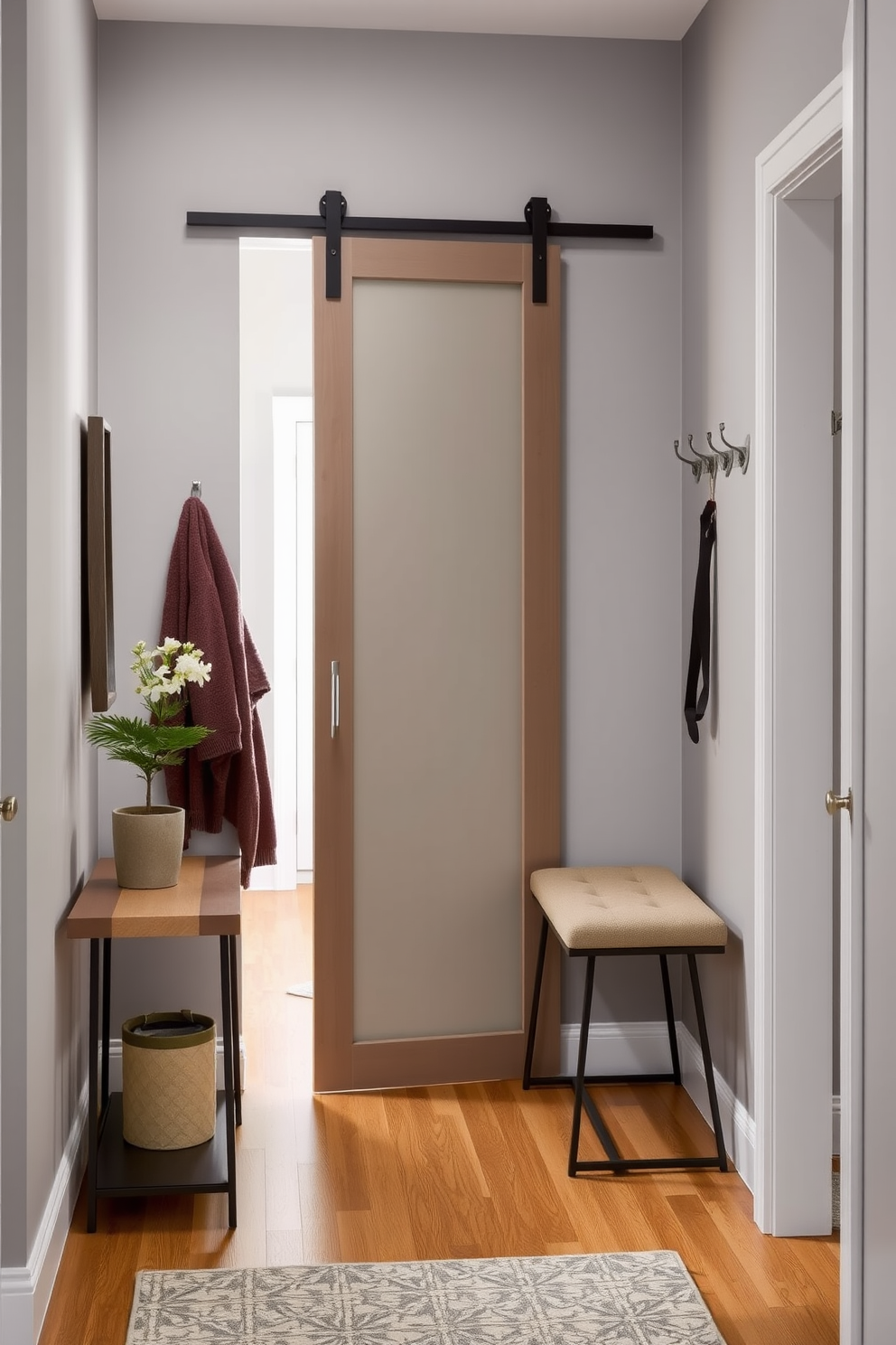 A small foyer featuring a sleek sliding door that maximizes space and enhances accessibility. The walls are painted in a soft gray hue, complemented by a minimalist console table adorned with a decorative mirror and a small potted plant. The flooring is a warm wood finish that adds a cozy feel, while a stylish bench provides a convenient seating area. A few hooks on the wall offer practical storage for coats and bags, creating an inviting and organized entryway.