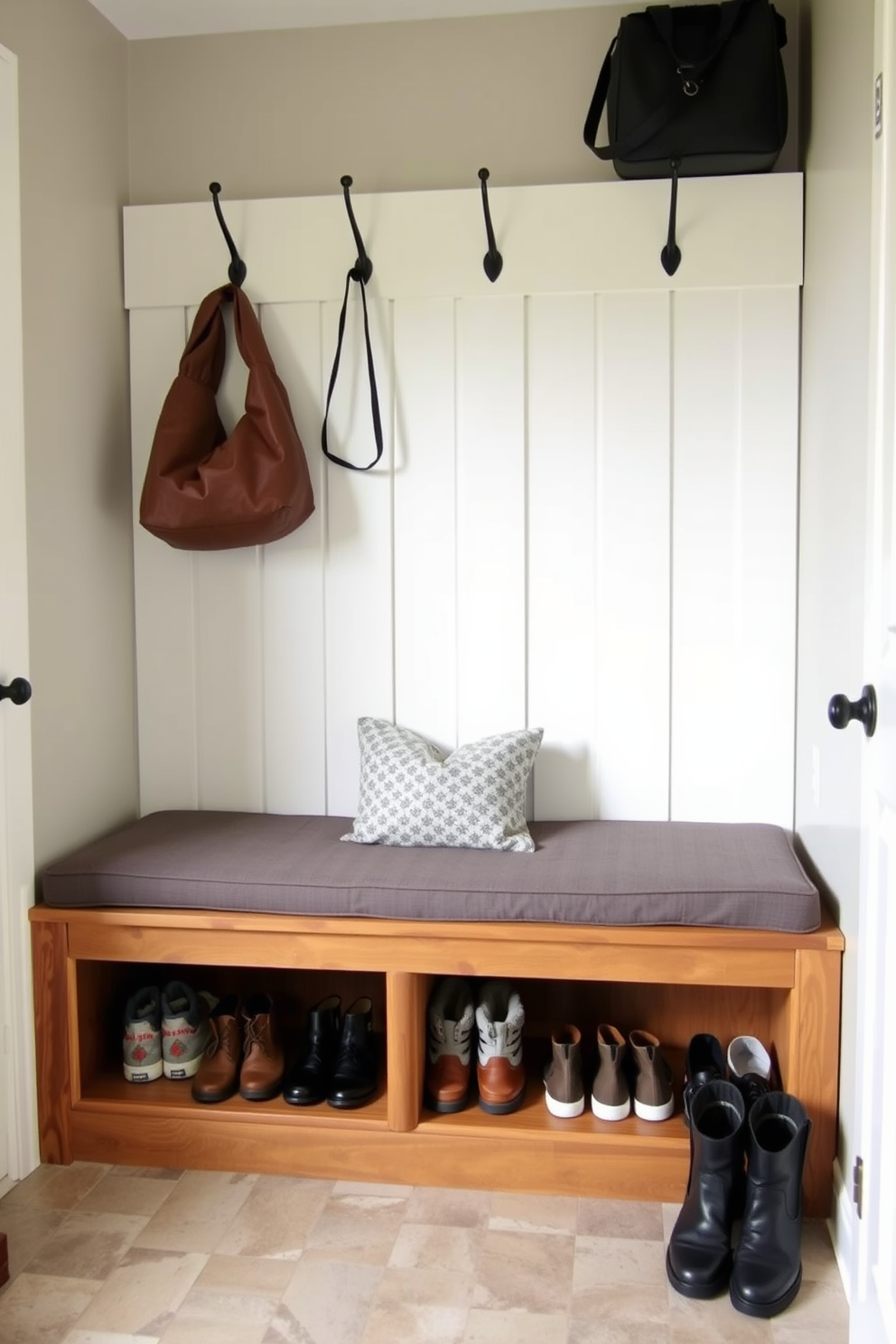 A multi-functional bench with seating is placed in a small mudroom, providing a cozy spot to put on or take off shoes. The bench features built-in storage underneath for shoes and outdoor gear, while hooks on the wall above offer a convenient place for coats and bags.