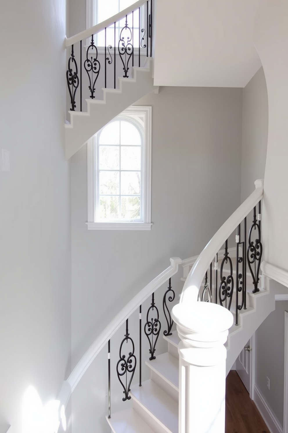 Elegant white spiral staircase with balusters. The staircase features a smooth white finish with intricate wrought iron balusters that add a touch of sophistication. Natural light floods the space, highlighting the elegant curves of the staircase. The surrounding walls are adorned with soft gray tones that complement the staircase's design.