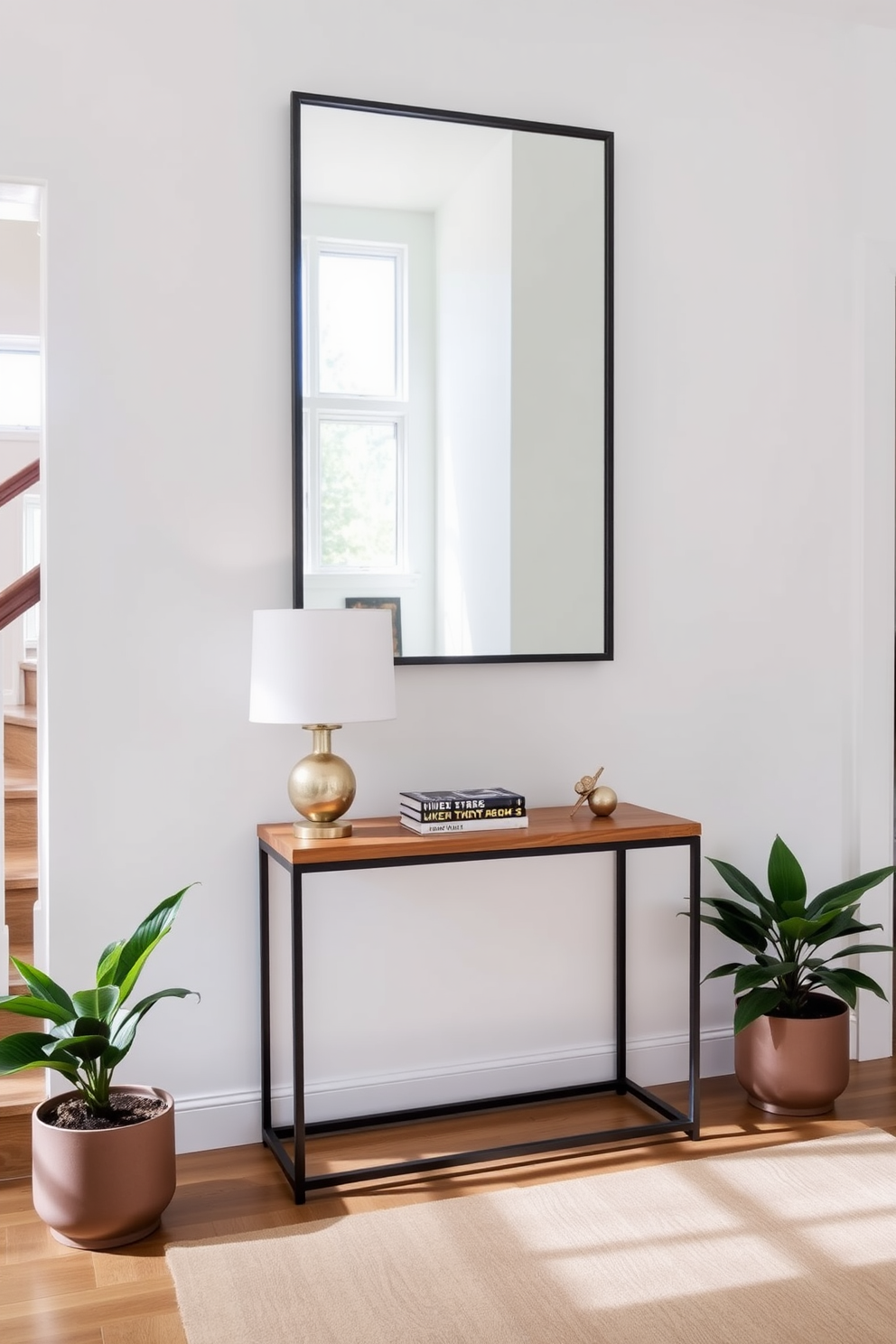 A stylish console table is positioned against the wall in a well-lit staircase landing. The table features a sleek design with a combination of wood and metal, topped with a decorative lamp and a few carefully arranged books. Above the console table, a large mirror reflects the natural light, enhancing the space's openness. Flanking the table are two potted plants that add a touch of greenery and warmth to the landing area.