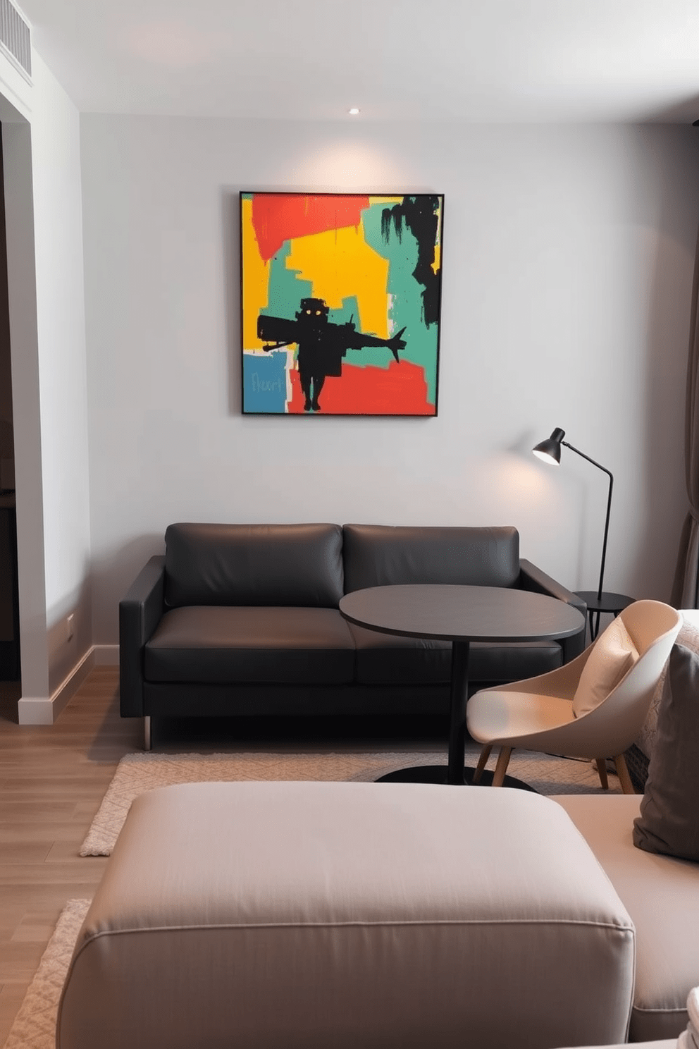 A stylish studio apartment featuring a statement piece of art as the focal point. The walls are painted in a soft gray hue, complementing the vibrant colors of the artwork that hangs prominently above a sleek, modern sofa. The living area is designed with multifunctional furniture, including a compact dining table that doubles as a workspace. Warm lighting fixtures create an inviting atmosphere, enhancing the overall aesthetic of the space.