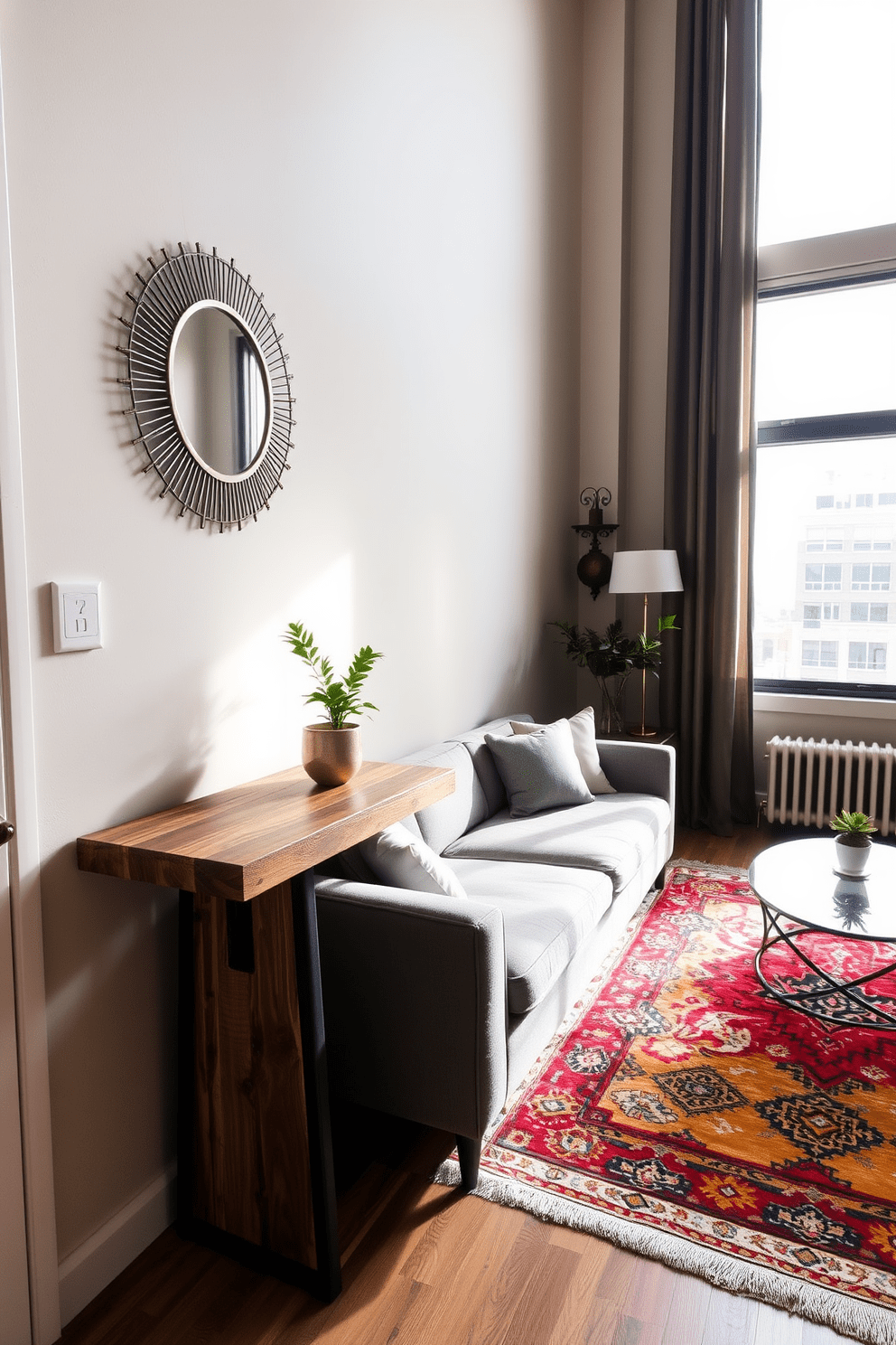 A stylish studio apartment featuring a small entryway console table against a wall. The console table is made of reclaimed wood, adorned with a decorative mirror above it and a small potted plant on top. The living area is designed with a cozy sofa in soft gray fabric, paired with a chic coffee table made of glass and metal. A vibrant area rug anchors the space, while large windows allow natural light to flood in, enhancing the warm atmosphere.