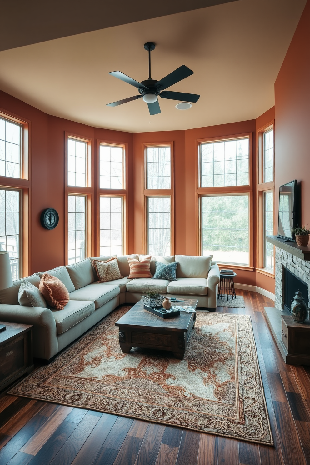 A cozy sunken living room featuring warm earth tones throughout the space. The walls are painted in a soft terracotta hue, complemented by a plush beige sectional sofa and rich wooden accents. A large area rug in muted browns and creams anchors the seating area, creating an inviting atmosphere. Floor-to-ceiling windows allow natural light to flood in, highlighting the textured throw pillows and a rustic coffee table.