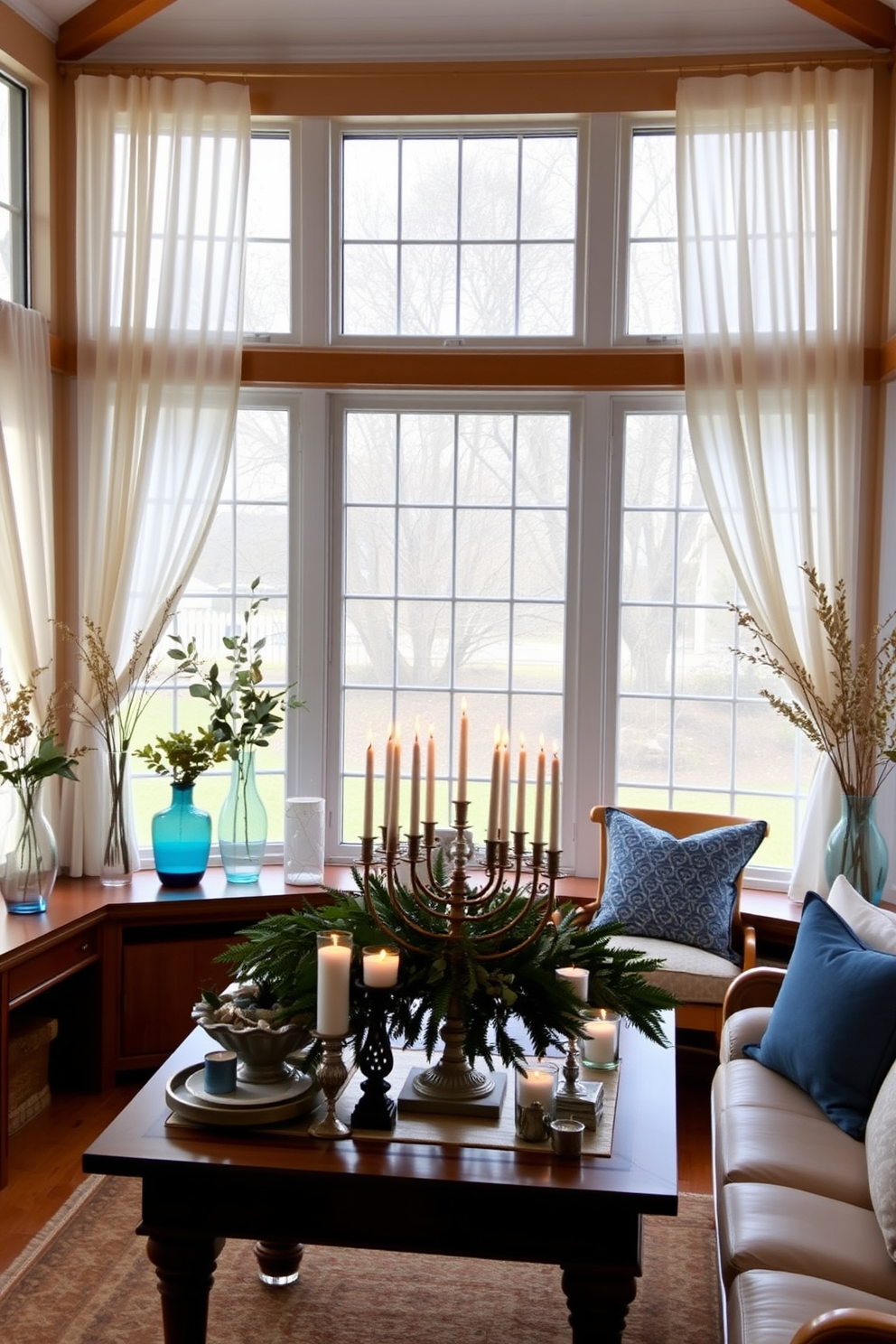 A bright sunroom filled with natural light features large windows adorned with sheer white curtains. In the corners, elegant vases filled with seasonal greenery bring a fresh touch, complementing the warm wooden furniture. For Hanukkah, the space is decorated with subtle blue and silver accents. A beautifully arranged table showcases a menorah surrounded by festive candles and decorative elements that enhance the cozy atmosphere.