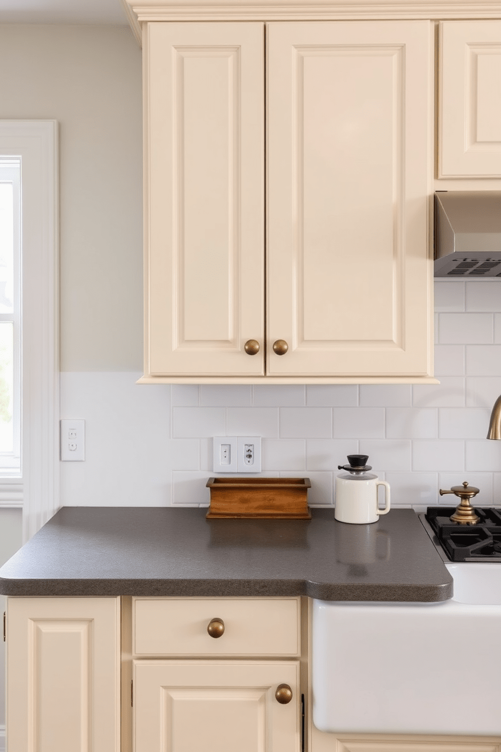 A timeless kitchen design featuring vintage hardware that adds character and charm. The cabinetry is painted in a soft cream color with brass knobs and handles, complemented by a farmhouse sink and a classic subway tile backsplash.