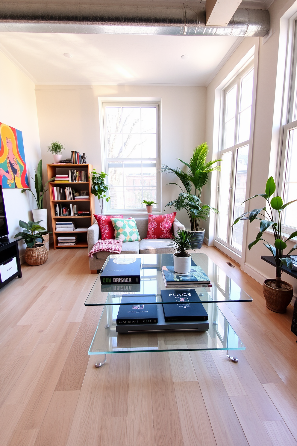 A stylish living area in a tiny apartment featuring a clear coffee table that enhances the sense of openness. The space includes a cozy sofa adorned with colorful cushions, a small bookshelf filled with books, and a vibrant piece of artwork on the wall. Natural light floods the room through large windows, illuminating the light wood flooring and creating a warm atmosphere. Potted plants are strategically placed to bring a touch of greenery, making the space feel more inviting and alive.