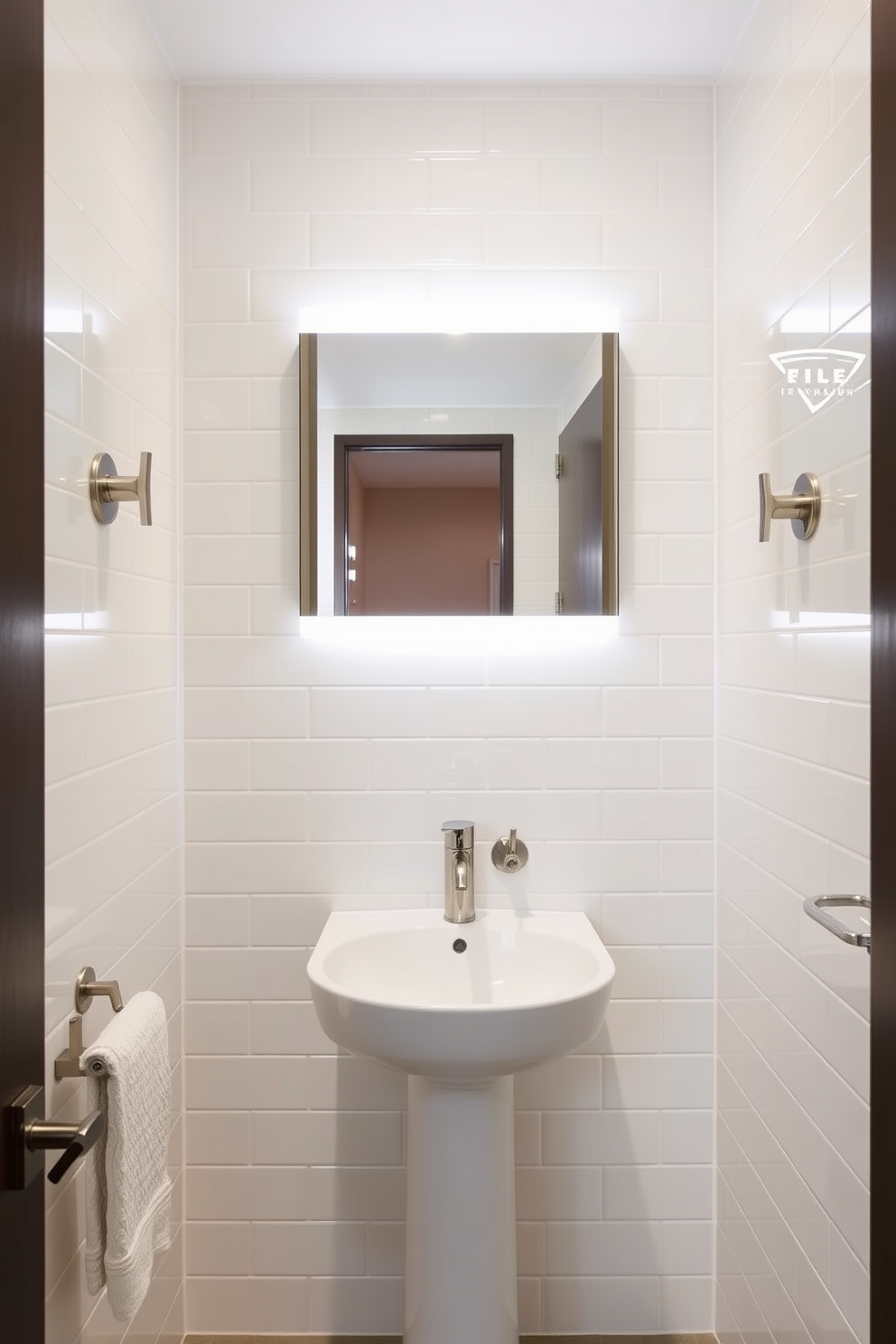 A stylish tiny powder room featuring wall-mounted faucets to maximize space efficiency. The walls are adorned with light-colored tiles, and a sleek pedestal sink is positioned beneath a modern mirror with integrated lighting.