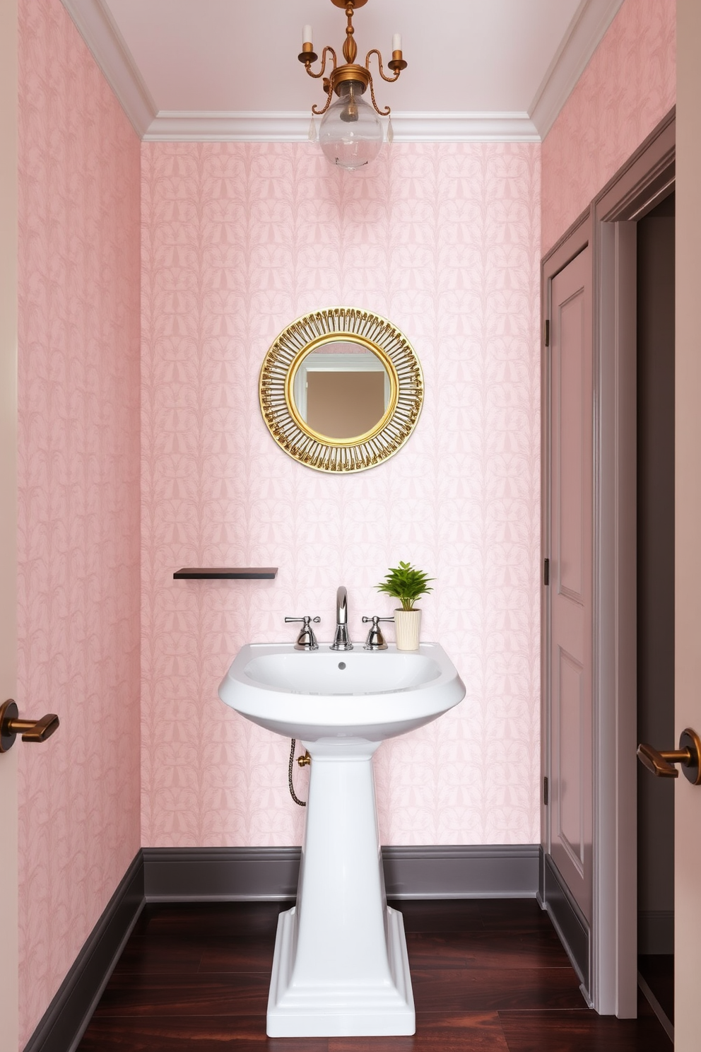 A stylish tiny powder room featuring a pedestal sink with a polished chrome faucet. The walls are adorned with a soft blush wallpaper, and a small chandelier hangs gracefully from the ceiling, adding a touch of elegance. The floor is finished with dark wood tiles that contrast beautifully with the light walls. A round mirror with a decorative gold frame is mounted above the sink, and a small potted plant sits on a floating shelf for a pop of greenery.