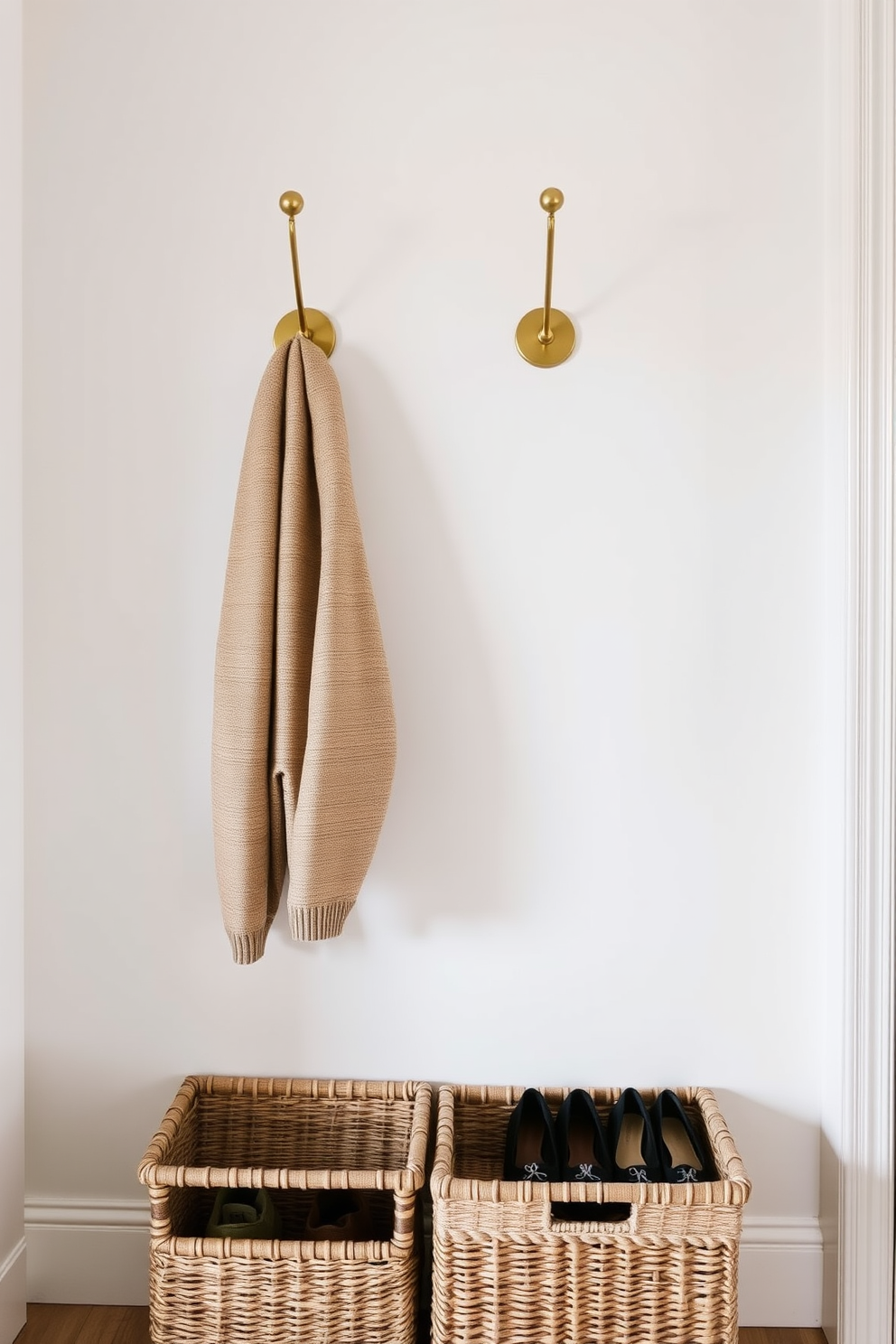 A stylish townhouse entryway features wall-mounted coat hooks made of brushed brass, providing a modern touch. Beneath the hooks, woven baskets in natural tones are neatly arranged, offering practical storage for shoes and accessories.