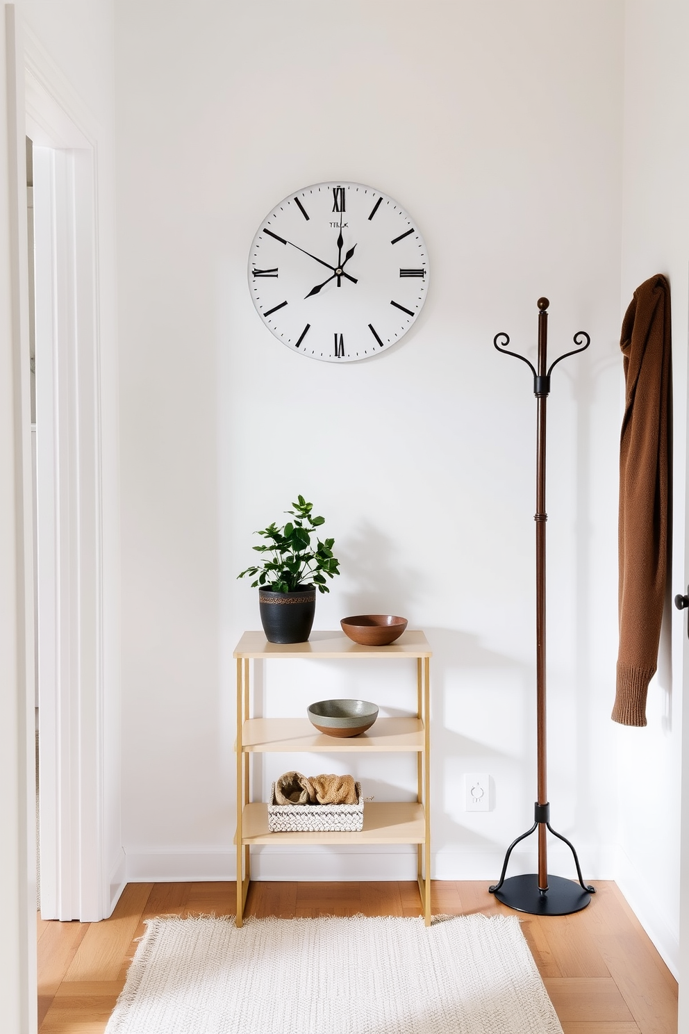 A simple wall clock is mounted on a white wall, featuring a minimalist design with black hour and minute hands. Below the clock, a narrow console table holds a small potted plant and a decorative bowl for keys. The entryway of the townhouse is adorned with a soft area rug in neutral tones, providing warmth and comfort. A stylish coat rack stands to one side, offering both functionality and an elegant touch to the space.