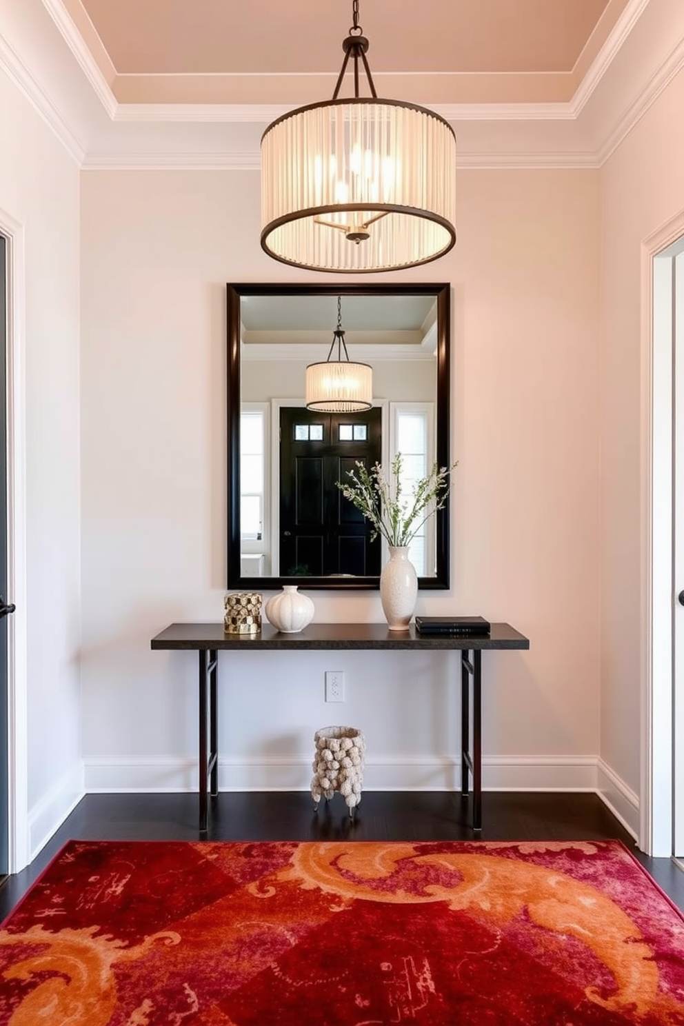 A statement lighting fixture hangs elegantly from the ceiling, casting a warm glow over the entryway. The space features a sleek console table adorned with decorative objects, complemented by a large mirror that enhances the sense of openness. The walls are painted in a soft neutral tone, creating a welcoming atmosphere. A stylish area rug in rich colors adds texture and warmth to the floor, inviting guests into the townhouse.